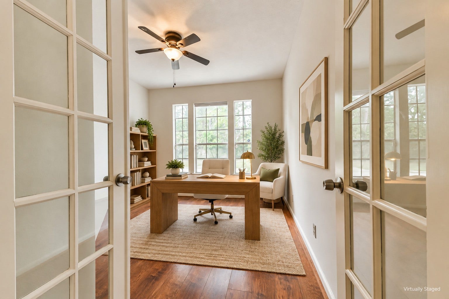 Virtually staged  French doors create a separate space for focused work, reading, or creative projects. Natural light keeps the room inviting, making working from home feel comfortably connected to life at home.