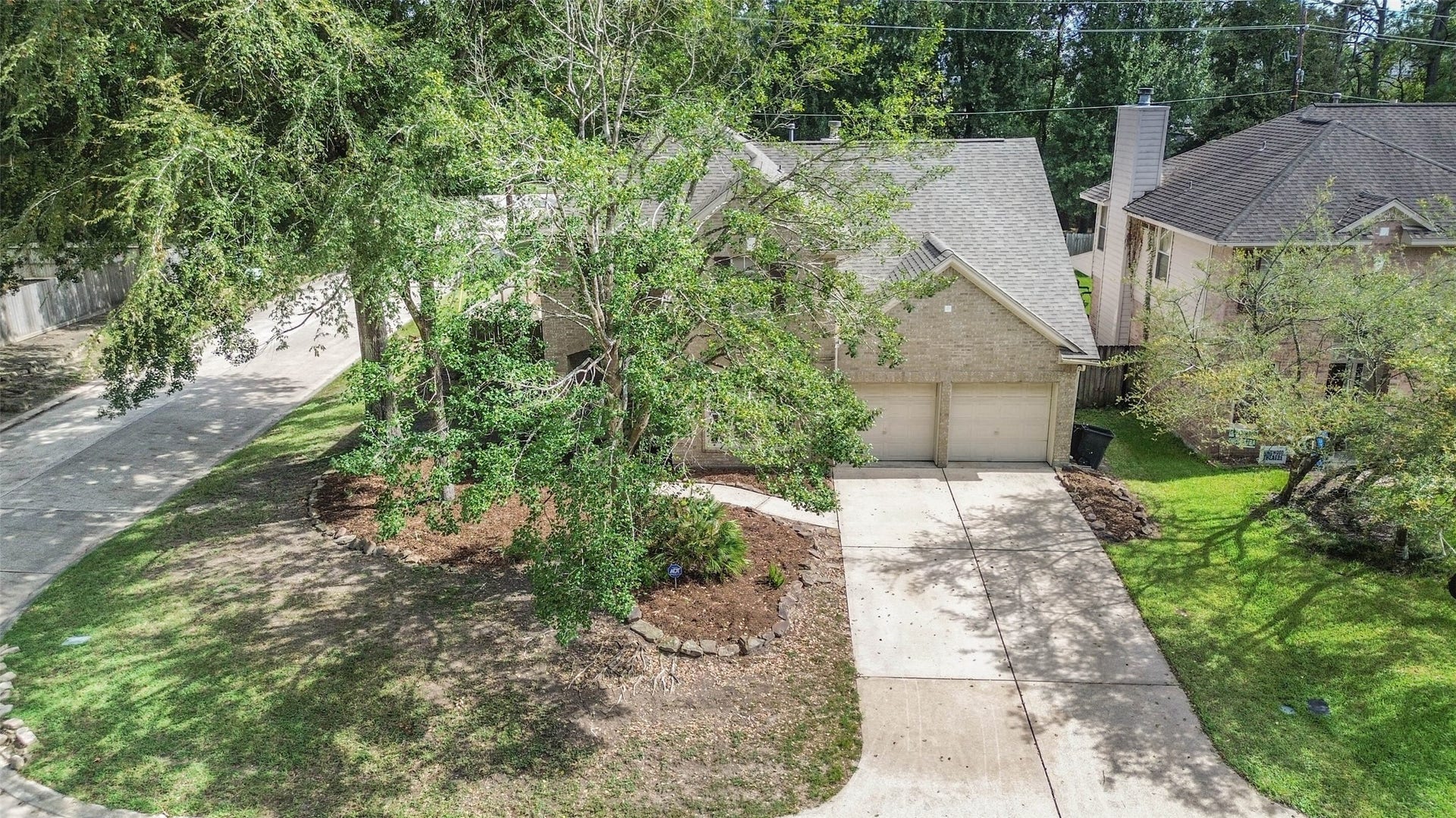 Come home to mature trees and a welcoming brick exterior that give this corner property its inviting character. A two-car garage and spacious driveway bring everyday convenience to a setting softened by greenery.