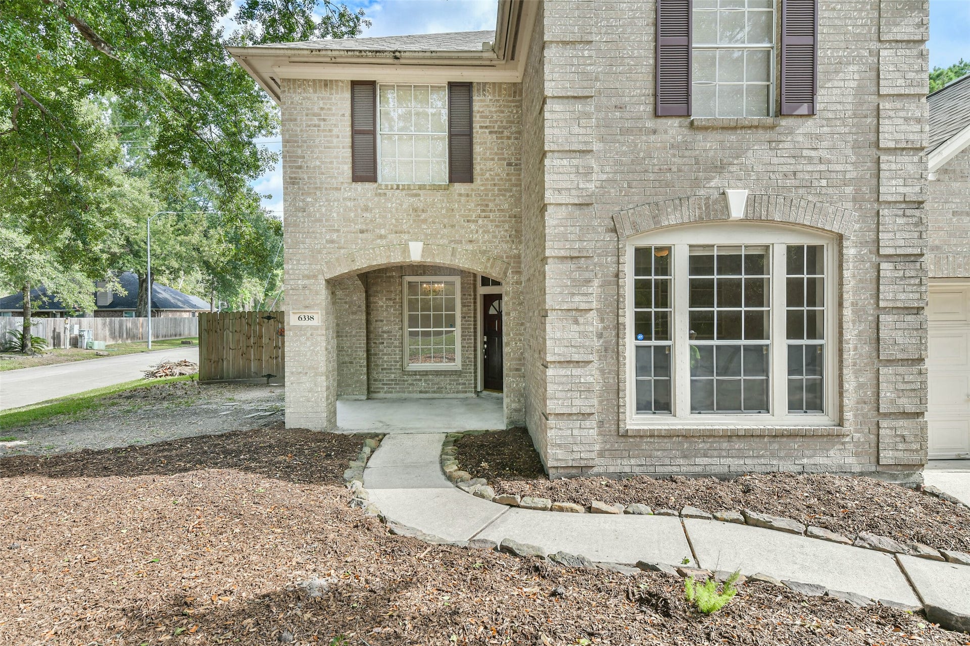 A sheltered welcome for guests and a convenient place to pause while finding your keys. The arched brick porch and curved approach create an inviting entrance, ready for seasonal planters and a few touches that make coming home feel personal.