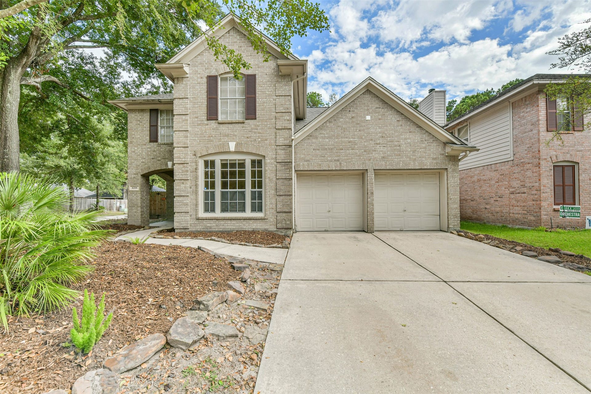 A welcoming arrival, from the broad driveway and two-car garage to the curved walkway leading toward the covered entry. Classic brickwork, shutter accents and mature trees give the home character before you step inside.