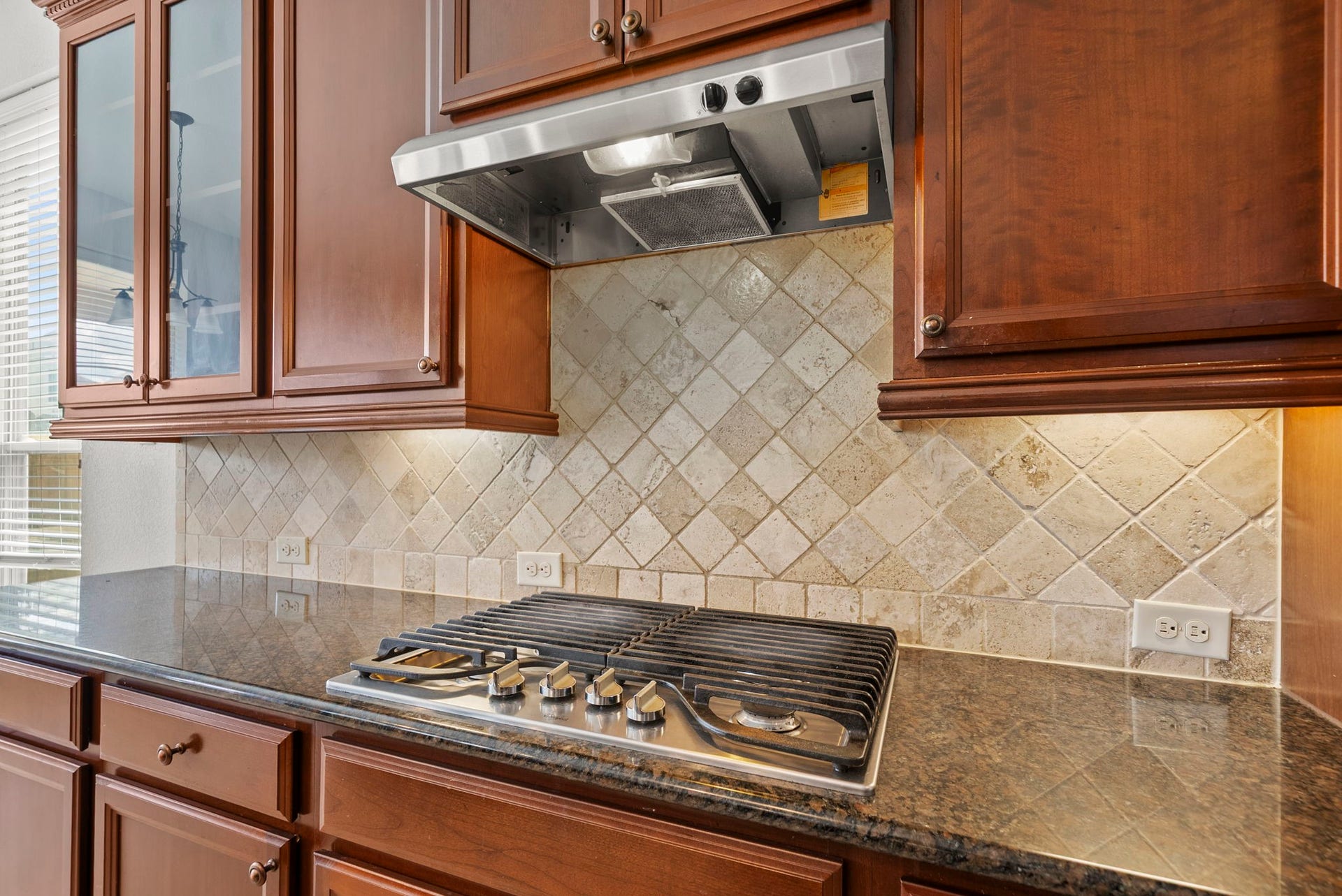 26111 Tintagel Lane, Kingwood, TX 77339 Gourmet gas cooktop is beautifully framed by an elegant travertine backsplash and gleaming granite counters, a chef's dream come true!