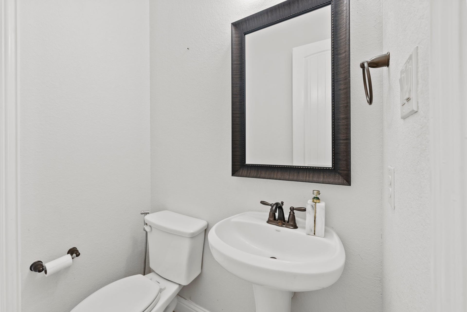 26111 Tintagel Lane, Kingwood, TX 77339 Charming half bath with pedestal sink, framed mirror, and classic fixtures in a clean, minimalist layout.