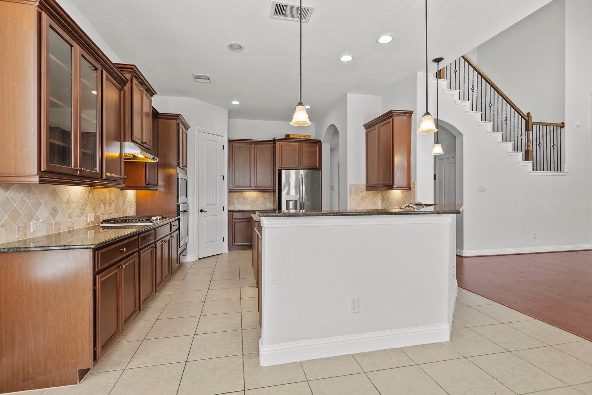 26111 Tintagel Lane, Kingwood, TX 77339 Open concept kitchen flows effortlessly into the grand staircase and living room, complete with pendant lighting, granite counters, and abundant cabinet storage!