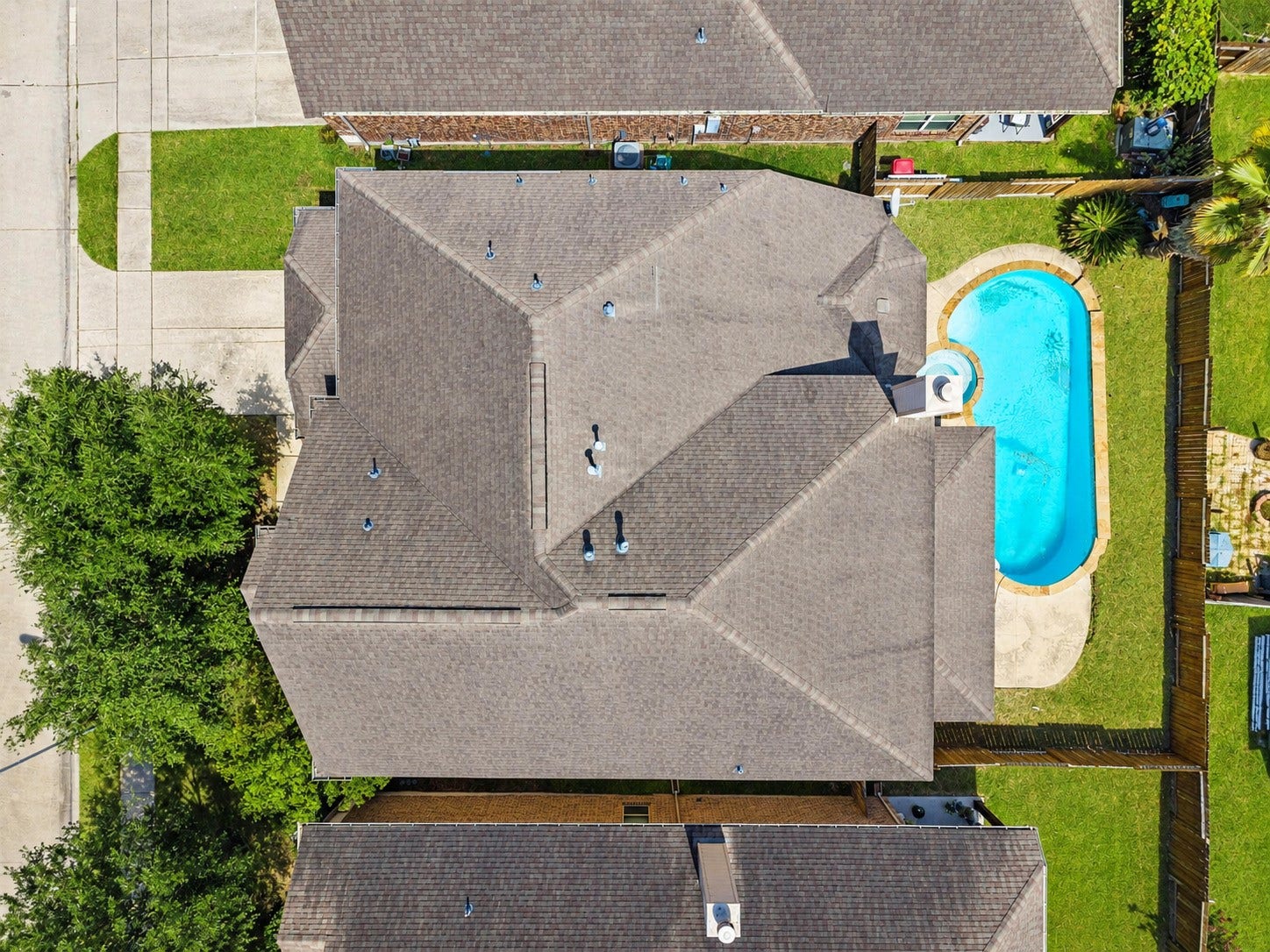 26111 Tintagel Lane, Kingwood, TX 77339 Breathtaking aerial perspective highlights the home's expansive roofline alongside a sparkling private pool, resort-style living right in the backyard!