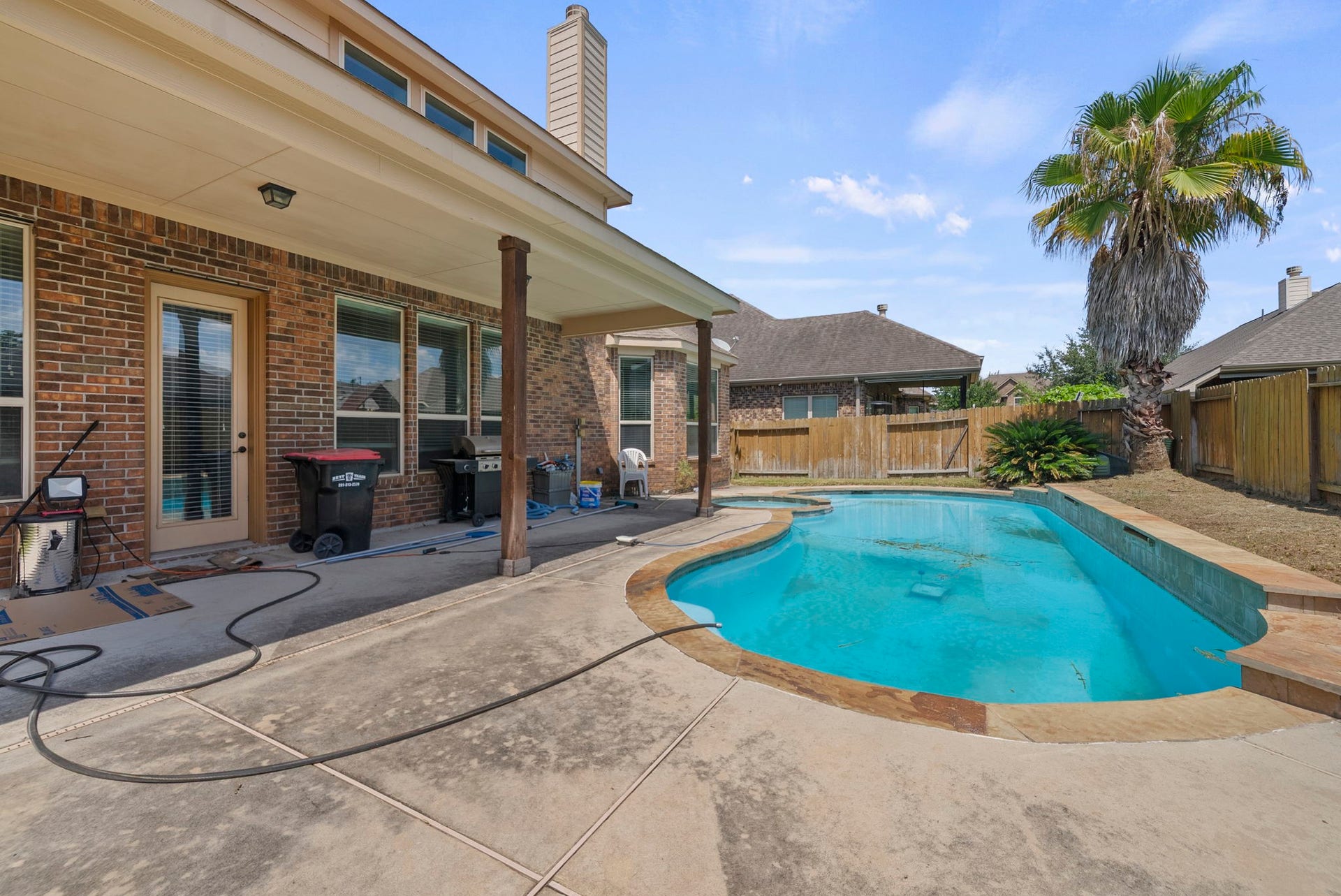 26111 Tintagel Lane, Kingwood, TX 77339 Resort-style pool and spa combo, framed by a swaying palm and expansive covered patio, sets the scene for endless summer fun!