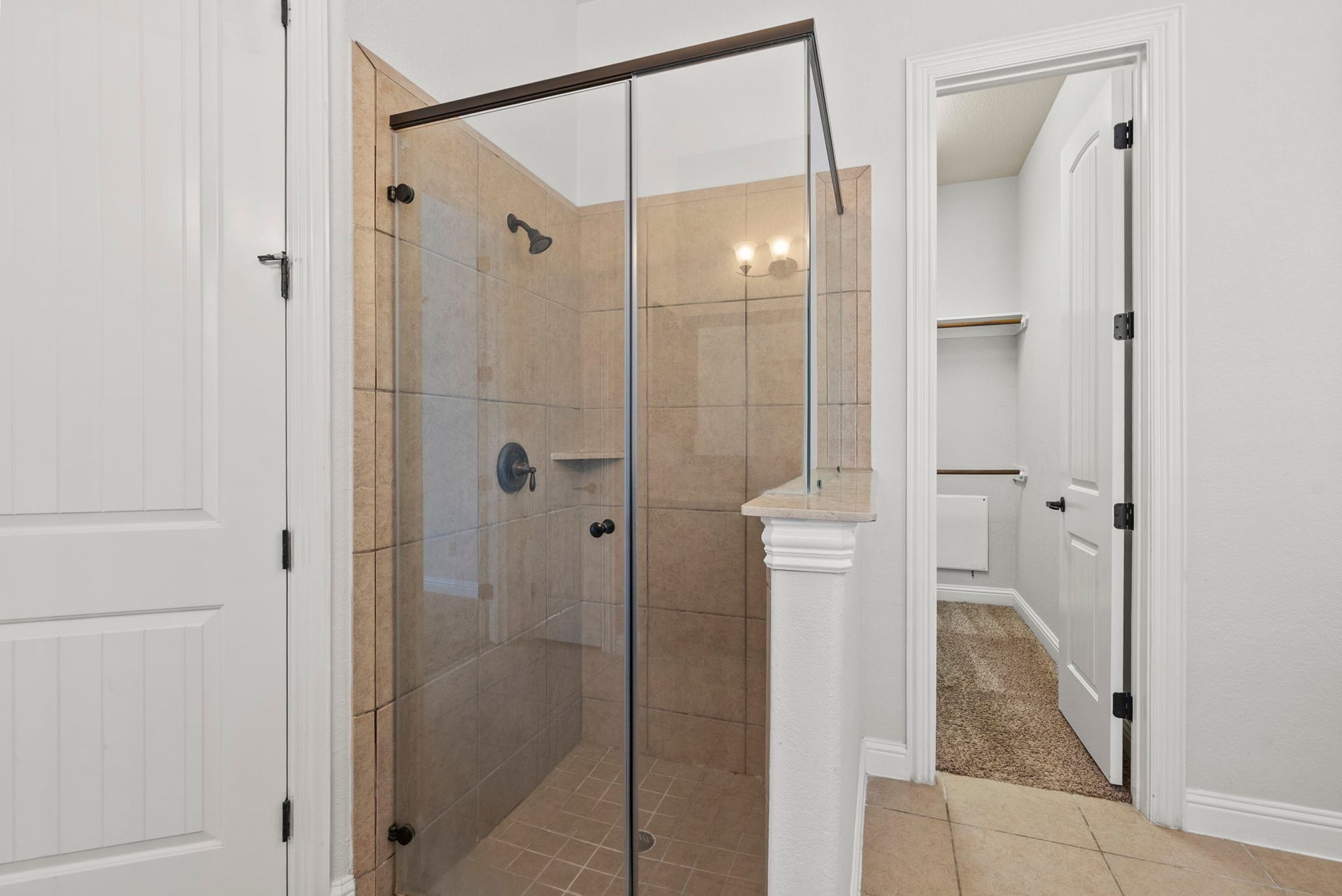 26111 Tintagel Lane, Kingwood, TX 77339 Beautifully tiled walk-in shower with a sleek frameless glass enclosure adds a spa-like touch to this well-appointed ensuite bath!