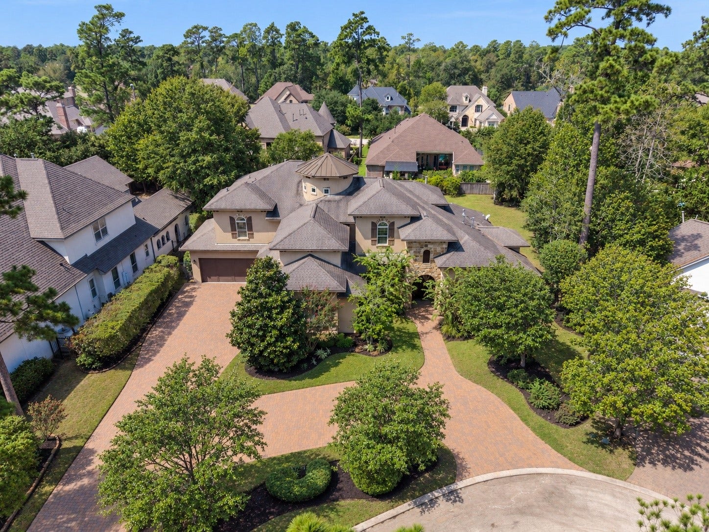 Circular drive showcases the homes distinctive architecture and lush wooded setting.