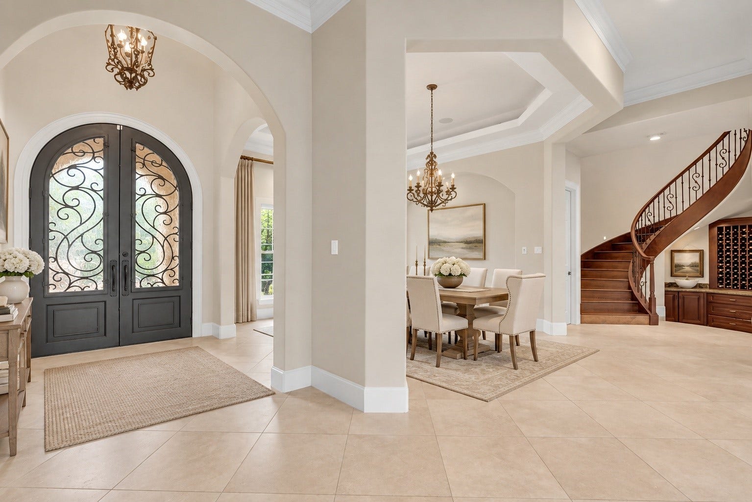 Grand entry showcasing custom iron doors and sweeping staircase.