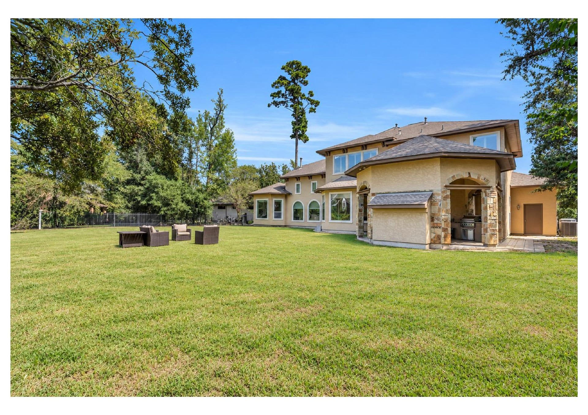 Expansive backyard with lush lawn and beautiful views of the homes rear elevation.