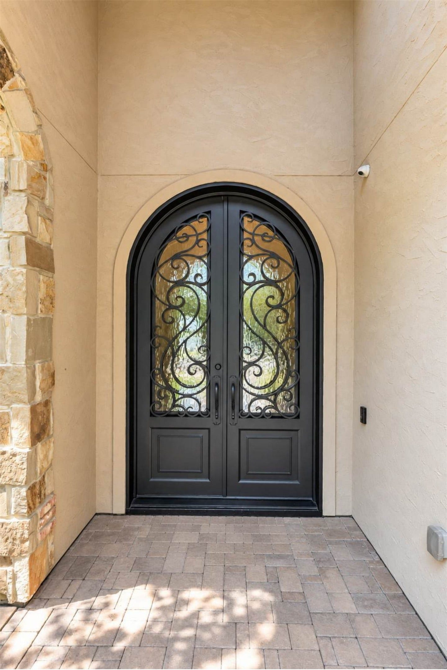 Grand arched entry featuring custom wrought-iron double doors.