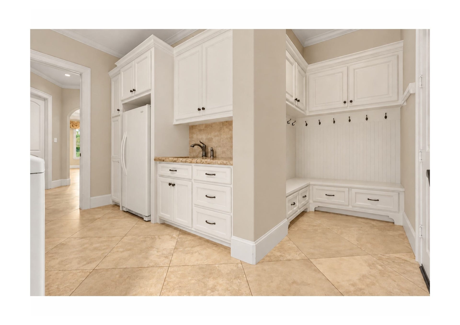 Well-appointed utility room on the first floor, with built-in cabinetry, sink and mudroom storage.