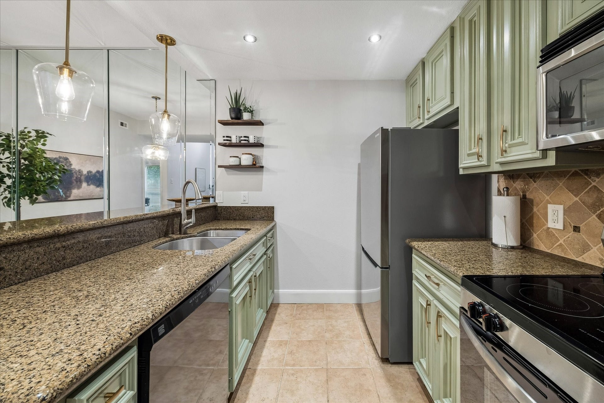 Kitchen featuring granite countertops, stainless steel appliances, a double-basin sink, and decorative tile backsplash.