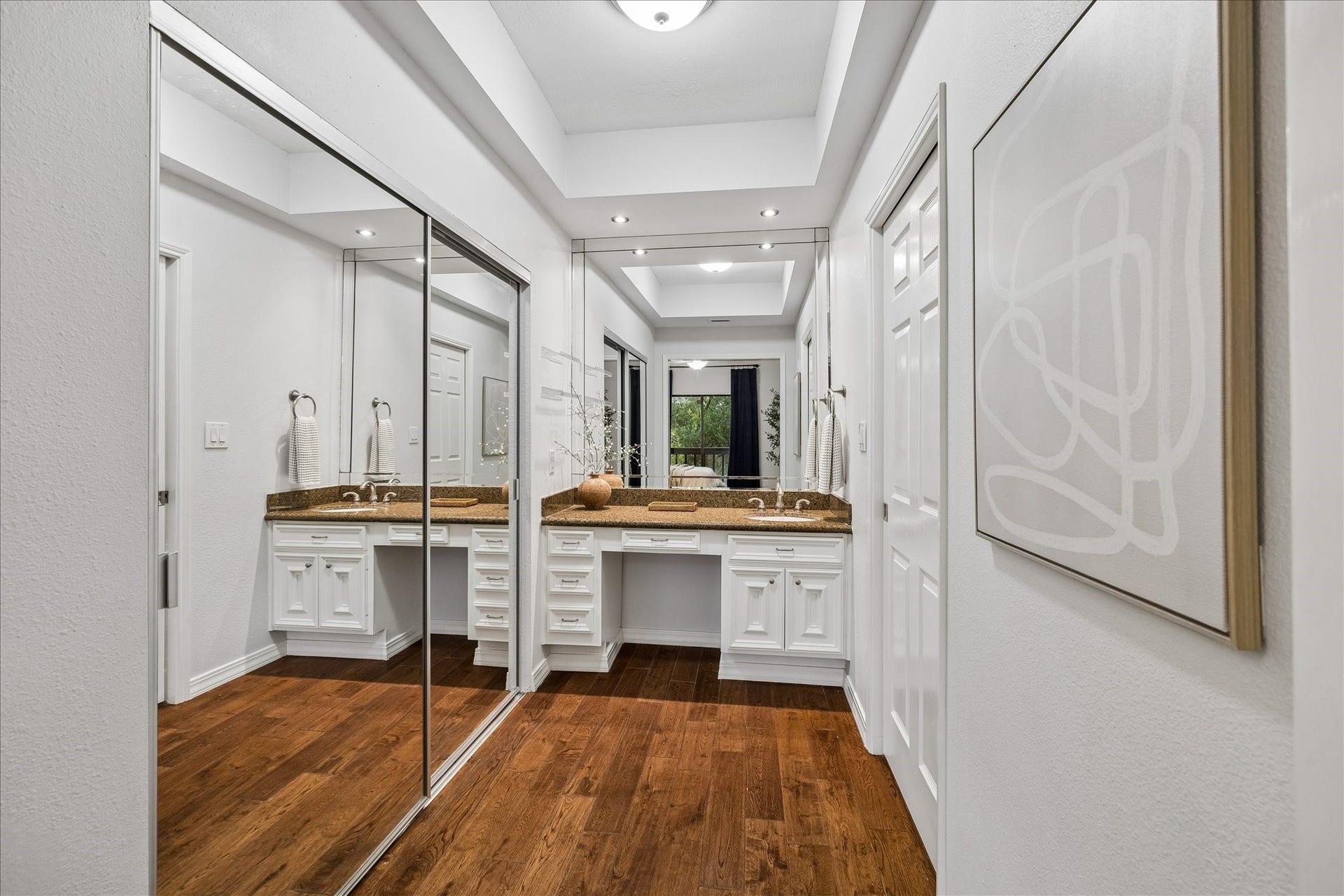 Generous vanity area with abundant cabinetry and mirrored closet doors.