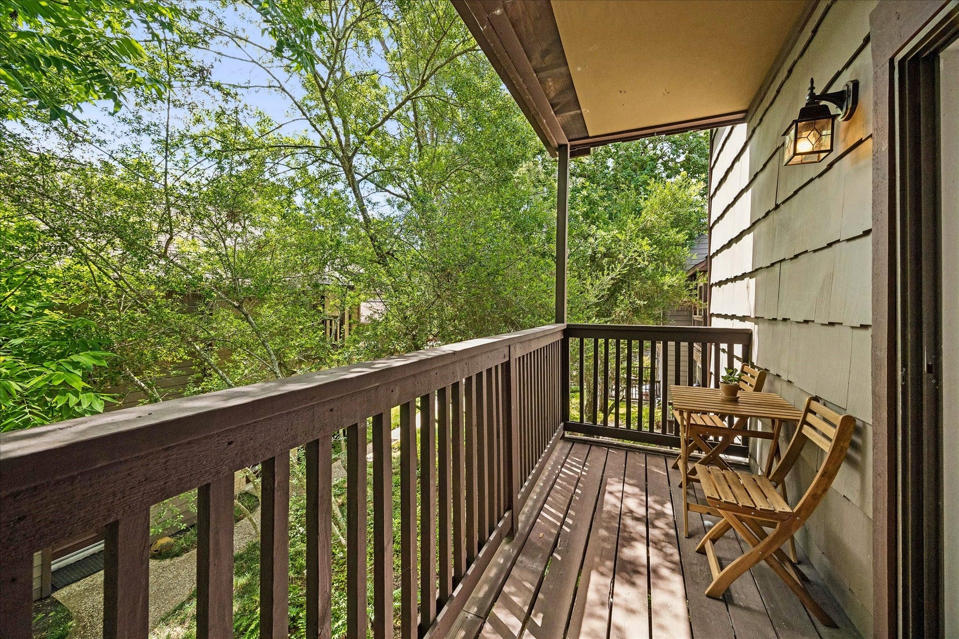Private balcony overlooking mature trees and lush green surroundings.