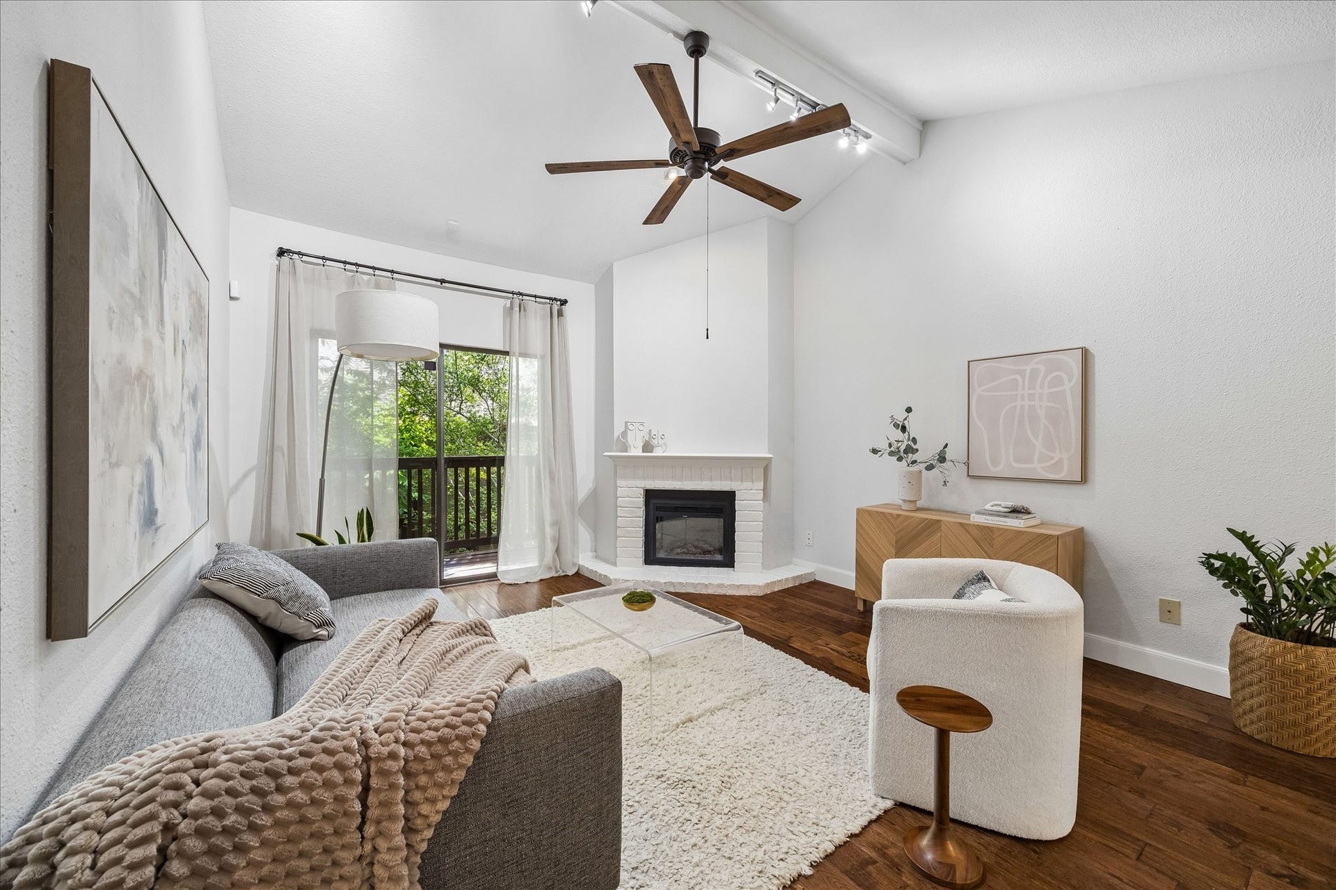 Bright living room featuring a soaring vaulted ceiling, electric fireplace, and private balcony access.