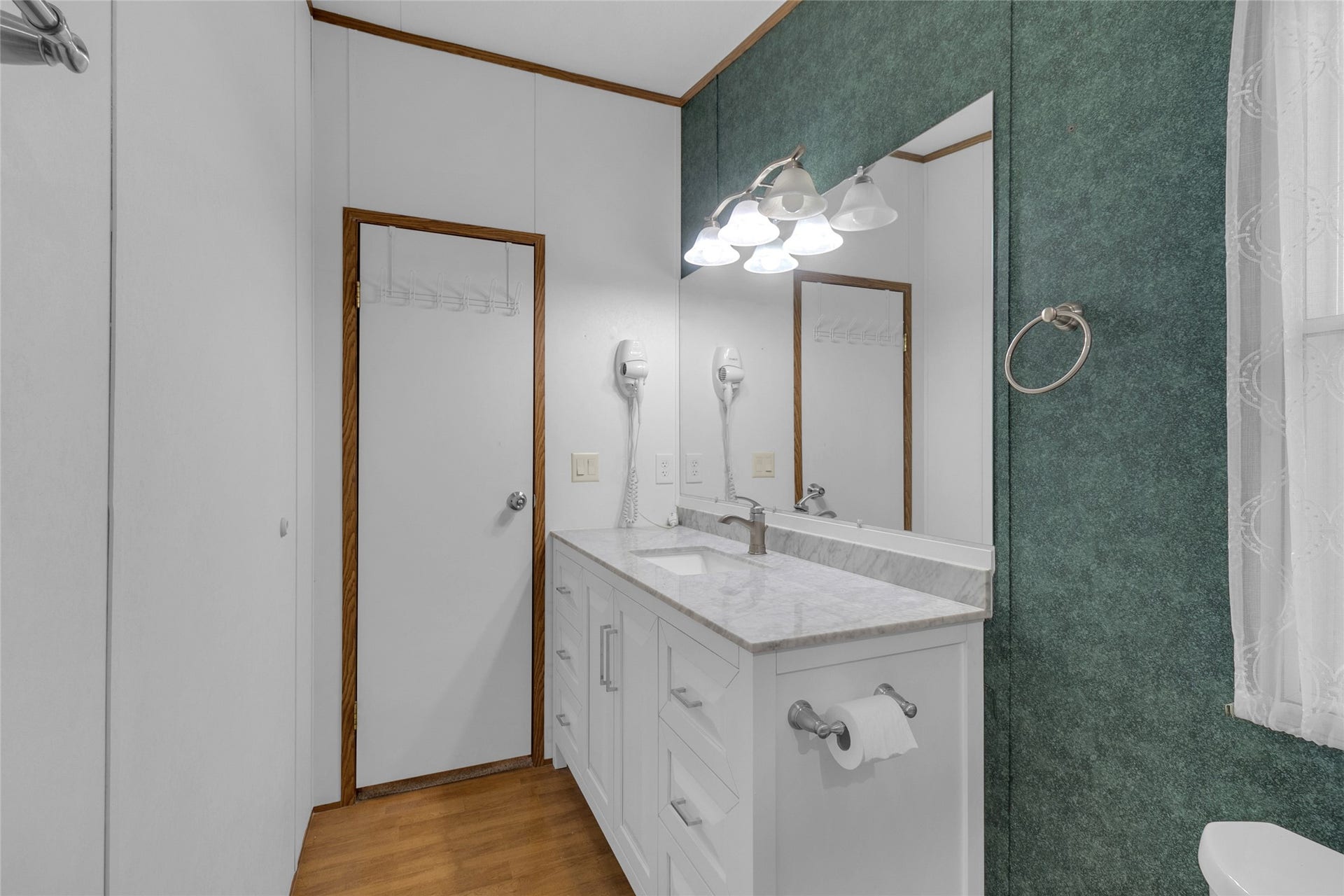 This bathroom features a sleek design with a large mirror, elegant lighting, and a white vanity.