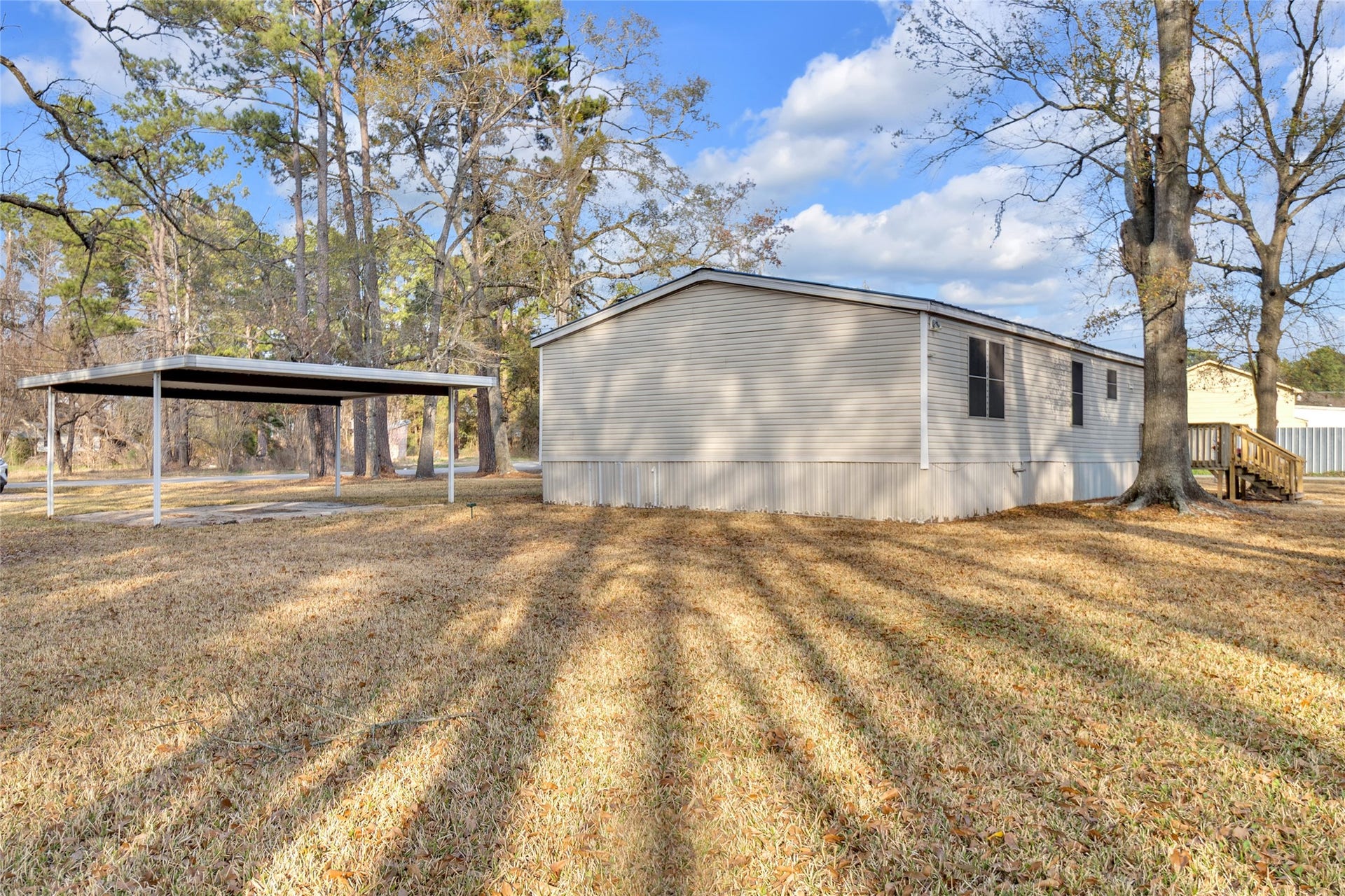 This property features a spacious mobile home with a well-maintained yard, mature trees, and a covered parking area. The home is positioned in a peaceful, natural setting, ideal for those seeking a quiet lifestyle.