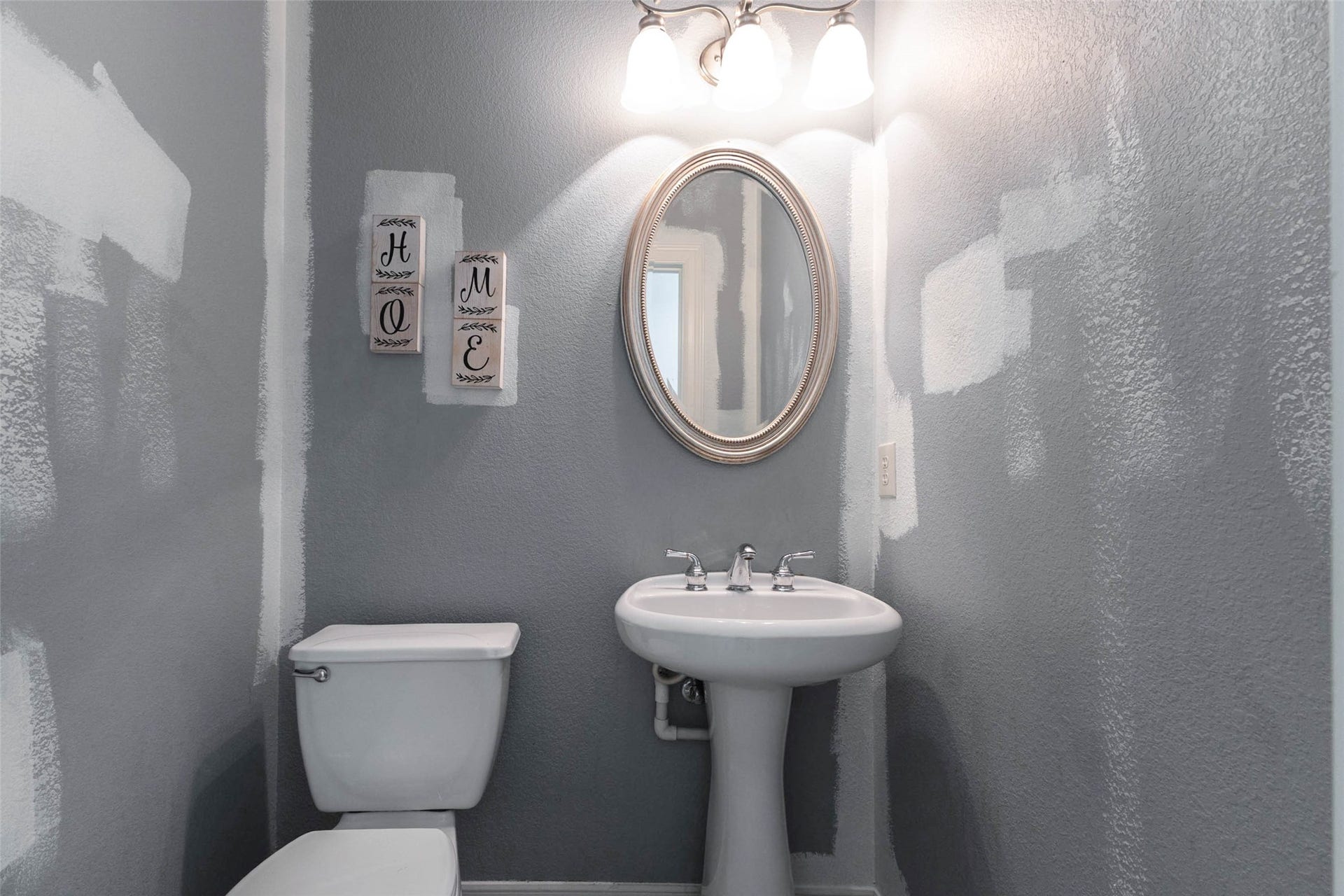 346 Skylark Street, Magnolia, TX 77355 Conveniently located half bath featuring a classic pedestal sink, oval mirror, and three-light vanity fixture. The partially painted walls offer an opportunity to add your own finishing touches.
