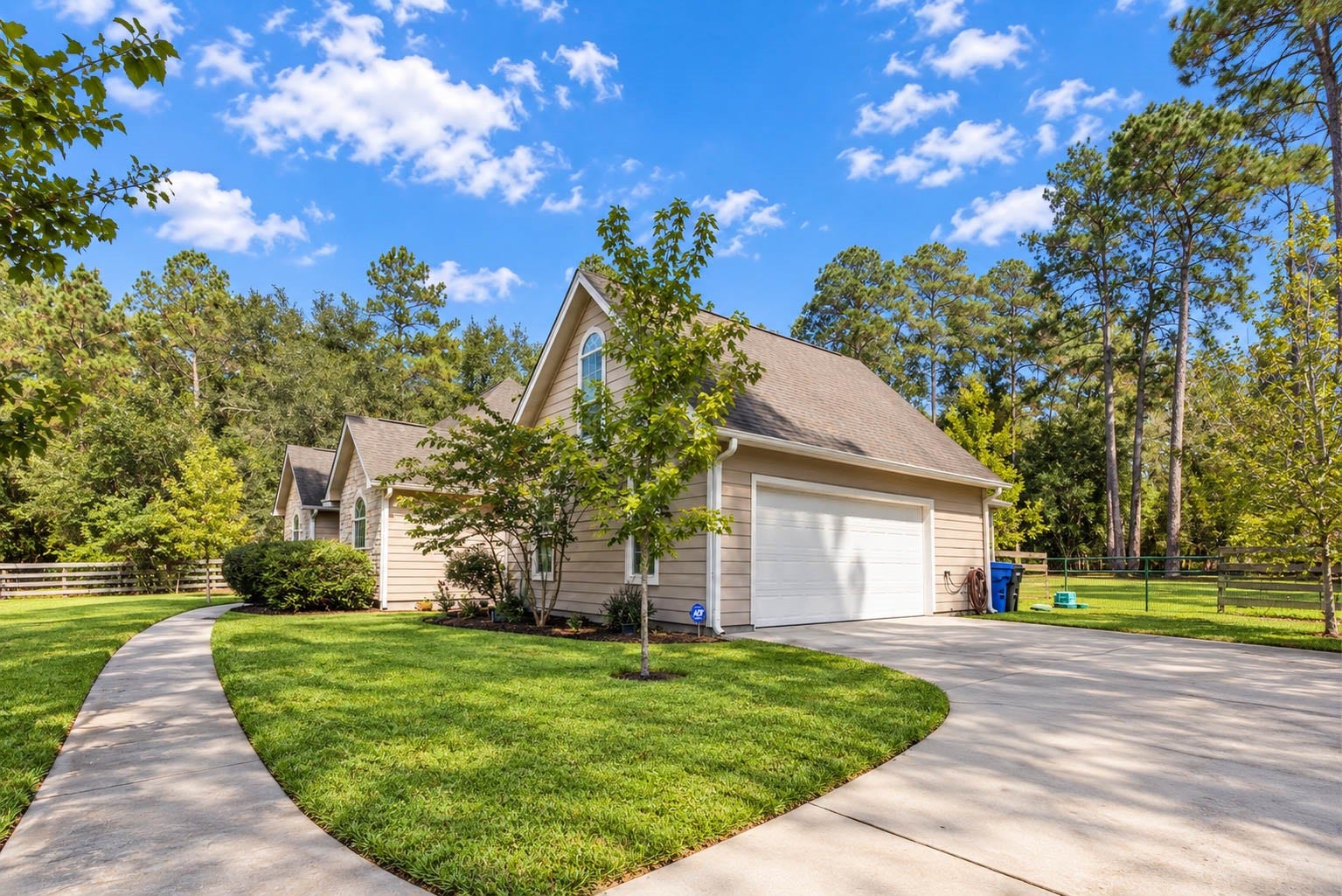 346 Skylark Street, Magnolia, TX 77355 A wide concrete driveway leads to the two-car attached garage, while a curved walkway provides a separate path to the front entrance. Notice the additional yard space and fencing along the side of the property.