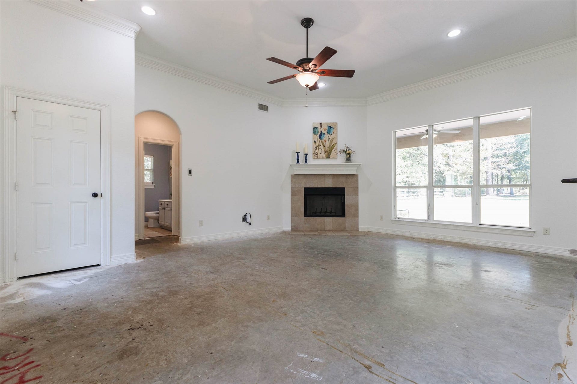 346 Skylark Street, Magnolia, TX 77355 A spacious living room with high ceilings, crown molding, a corner fireplace, and large windows overlooking the backyard. With the flooring removed, this room is a blank canvas for your choice of new flooring and personal style.