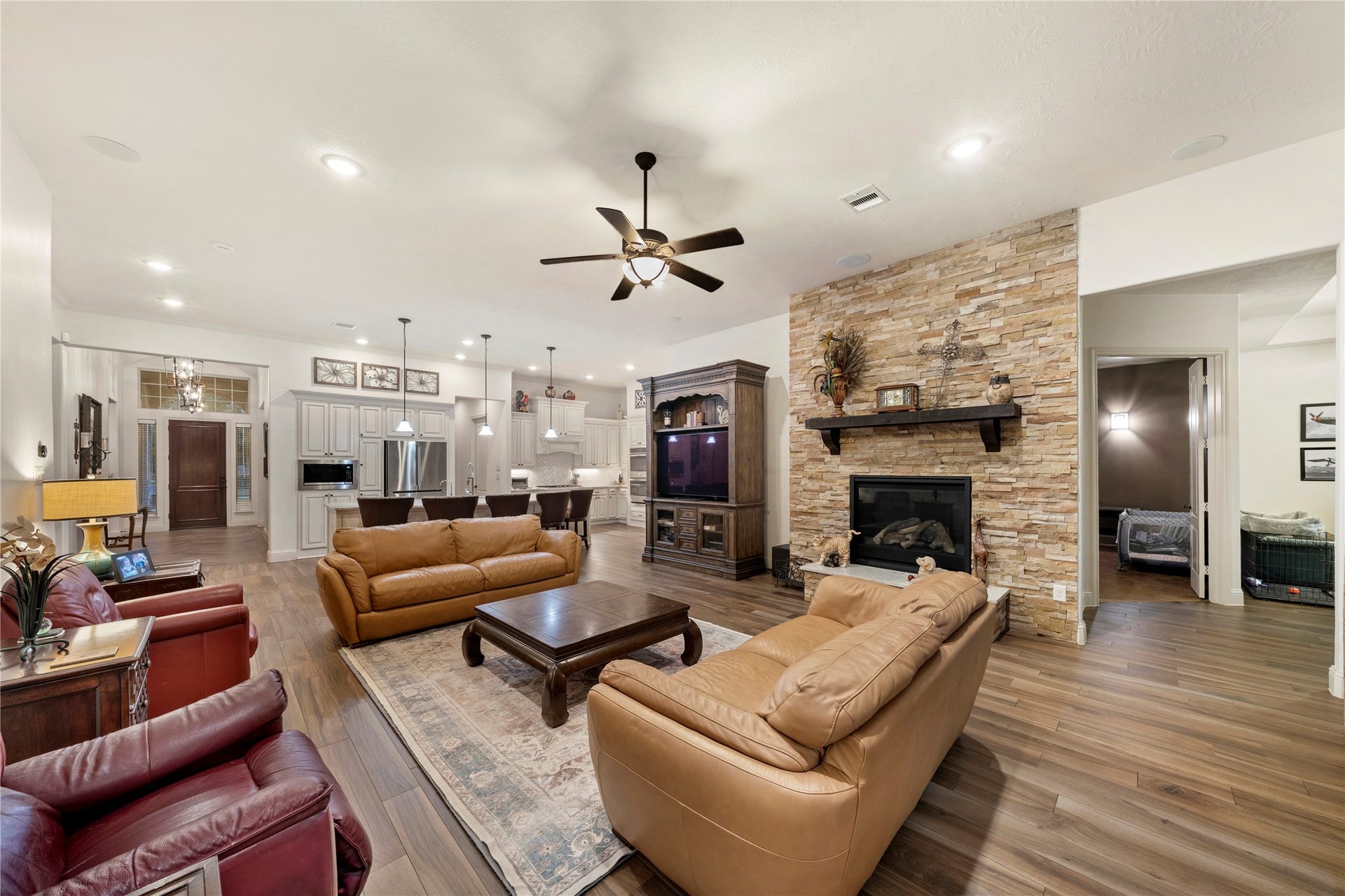 Spacious open-concept living area featuring a cozy stone fireplace, elegant Italian tile flooring, and a modern kitchen with sleek cabinetry and stainless steel appliances.