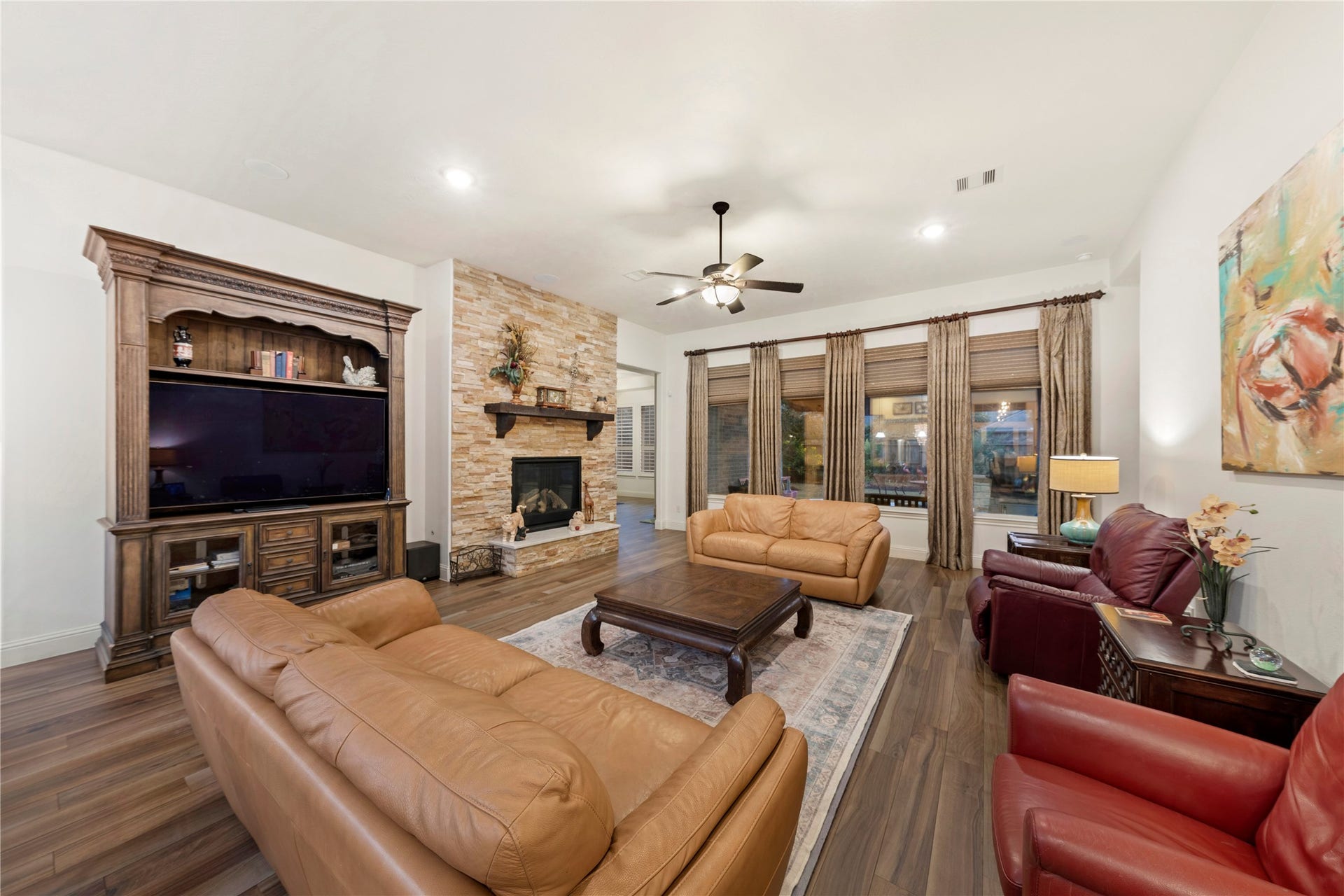 Spacious living room with elegant Italian tile floors, a cozy stone fireplace, and abundant natural light from large windows.