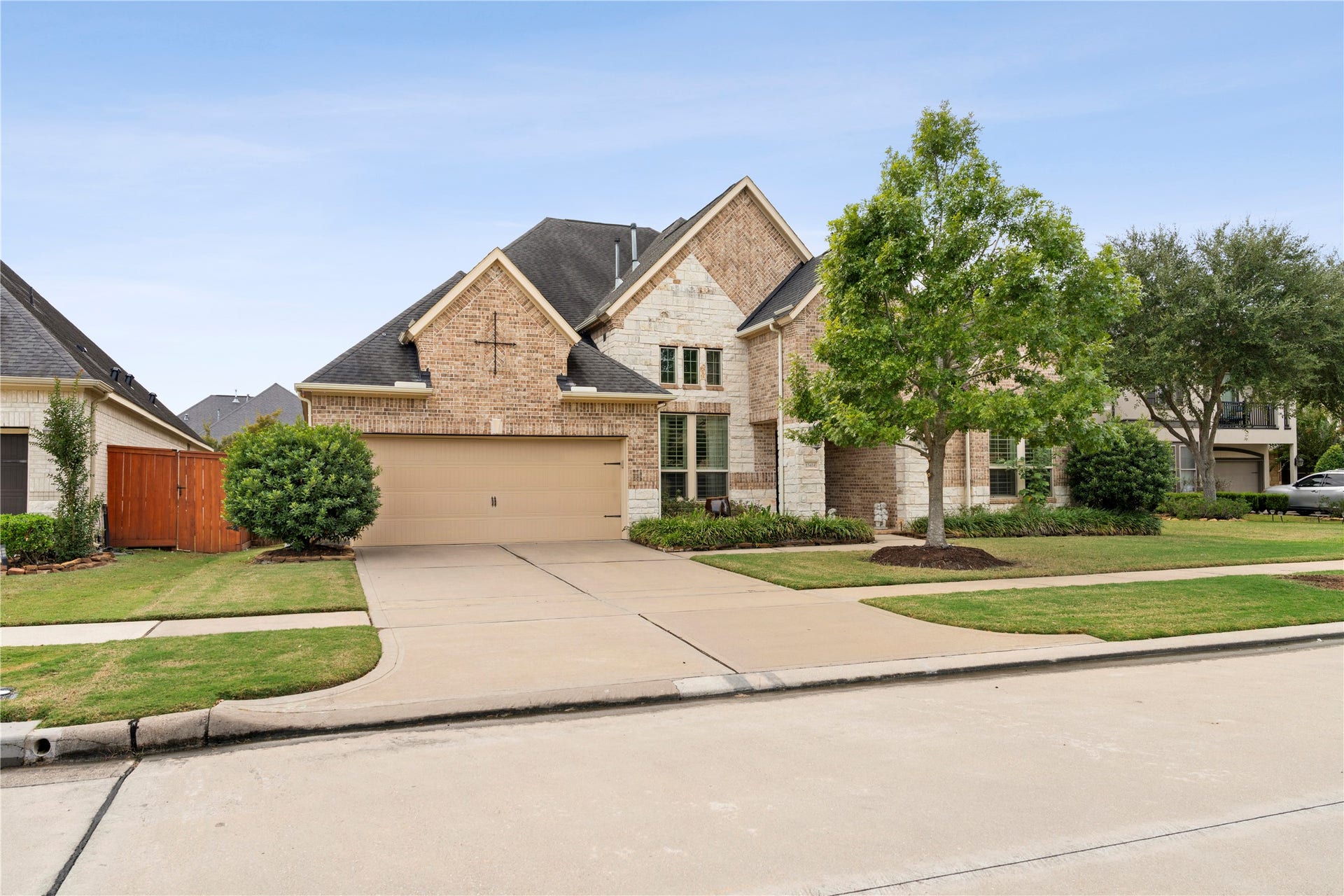 Expansive double-wide driveway leads to a spacious 3-car tandem garage with convenient built-in shelving, perfect for storage and organization.