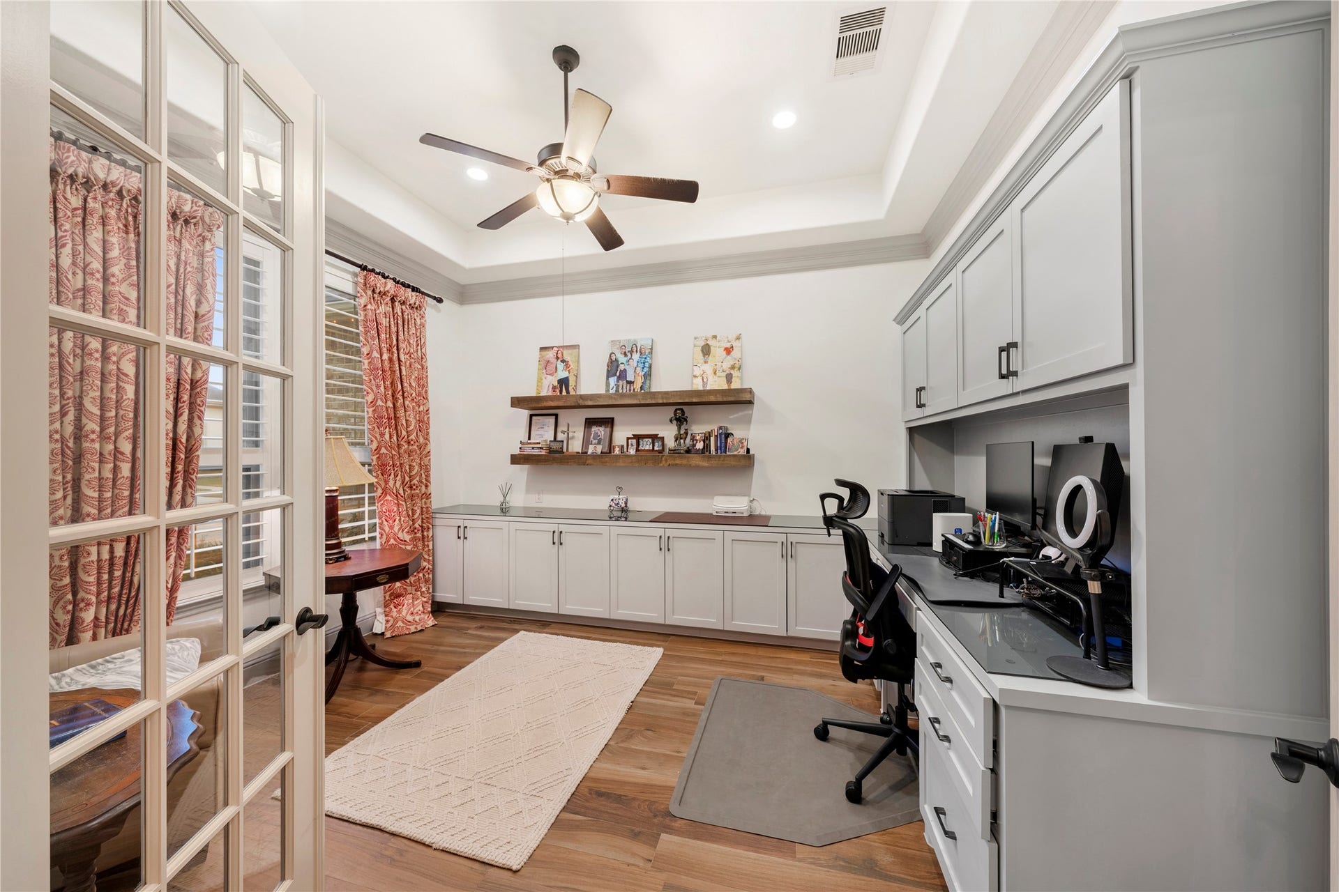 A spacious office greets you with elegant French doors and custom built-in cabinetry, offering both style and privacy.