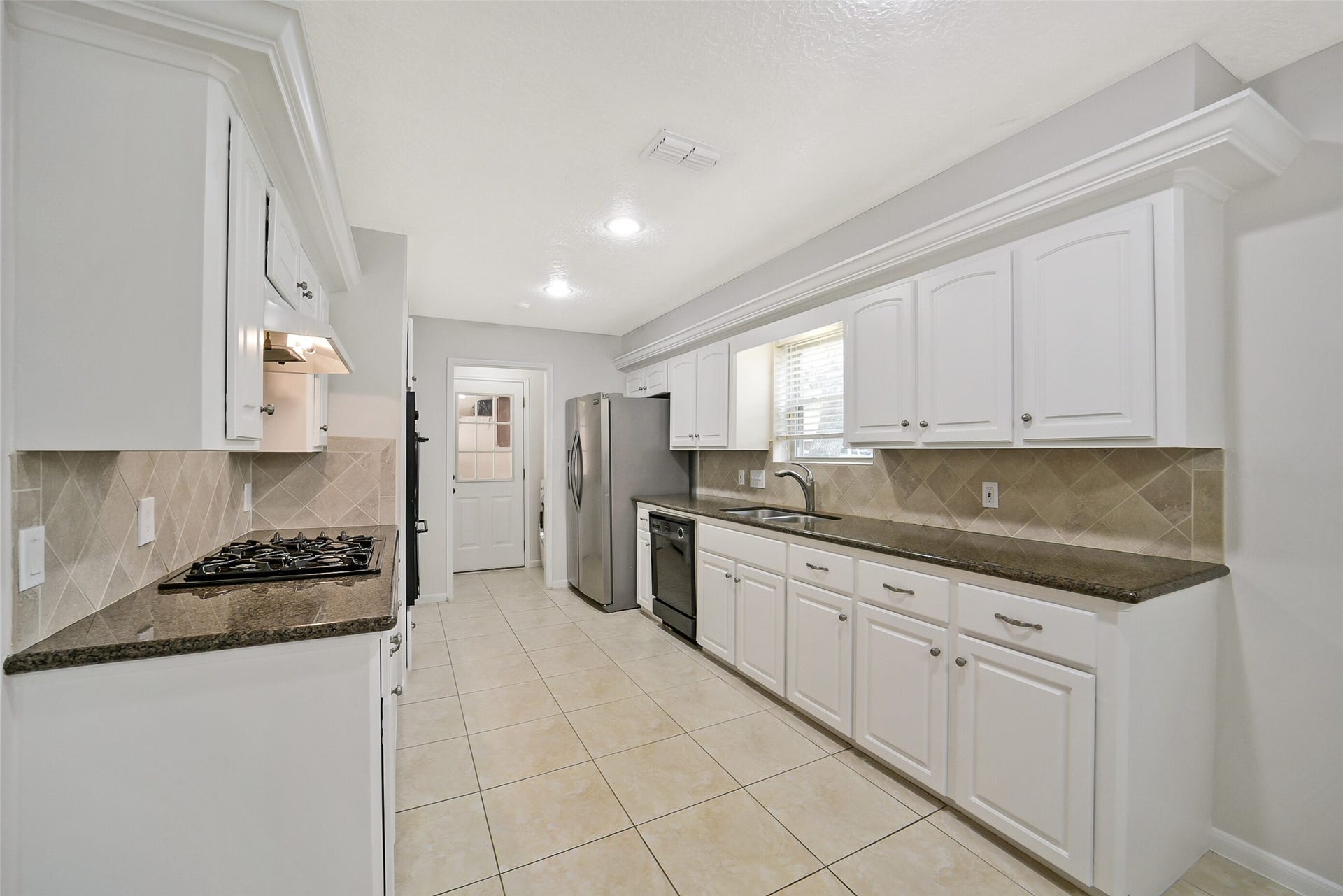 The kitchen features tile floors, granite counters with tile backsplash and recessed lighting.