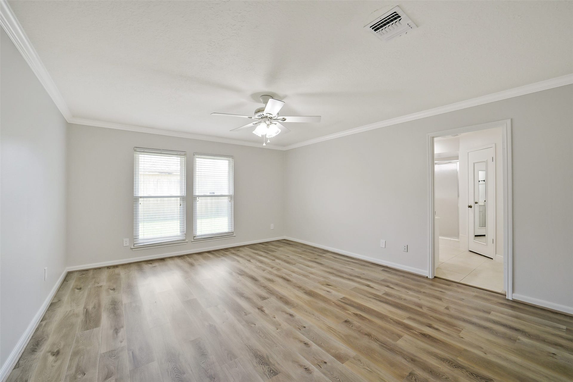 The primary bedroom features crown molding and a ceiling fan.