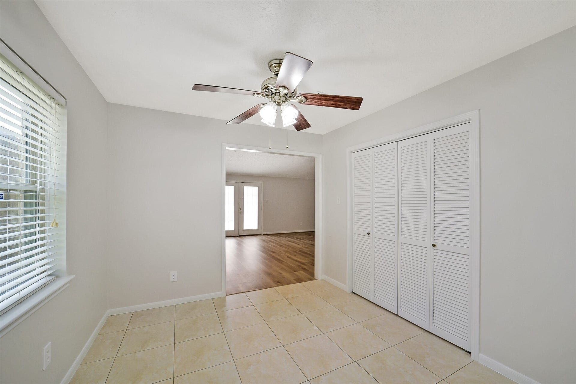 The breakfast room is just off to the side of the kitchen with tile floors and a ceiling fan. On the right is a second walk-in pantry.