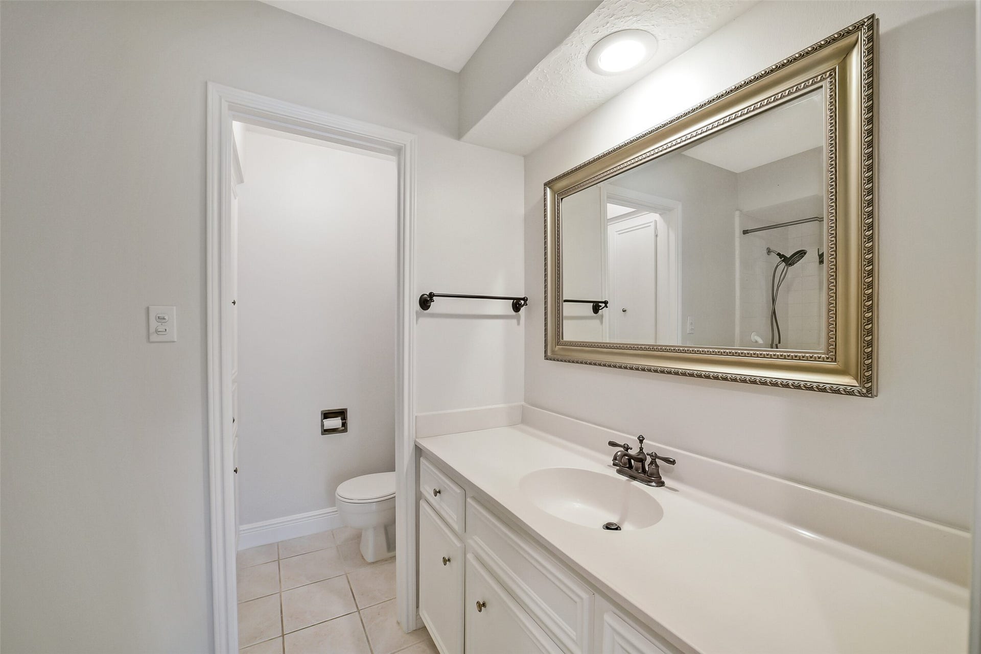 The second full bathroom is shared between bedroom #2 and bedroom #3. There is a single sink, framed mirror and tile floors.