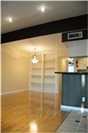 6001 Reims Road, #1202, Houston, TX 77036 This photo showcases a bright, open living area with polished wood flooring, built-in shelving, and recessed lighting. There's a partial view of a kitchen bar area, adding a modern touch.