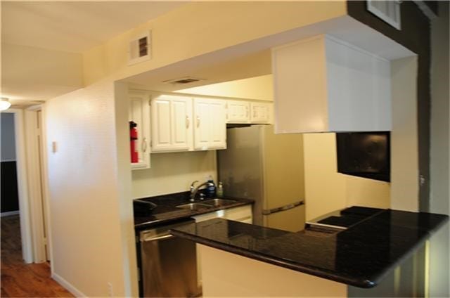 6001 Reims Road, #1202, Houston, TX 77036 Compact kitchen with a sleek black granite countertop, stainless steel appliances, and white cabinetry. It features an open layout with a breakfast bar, creating a modern and functional space.