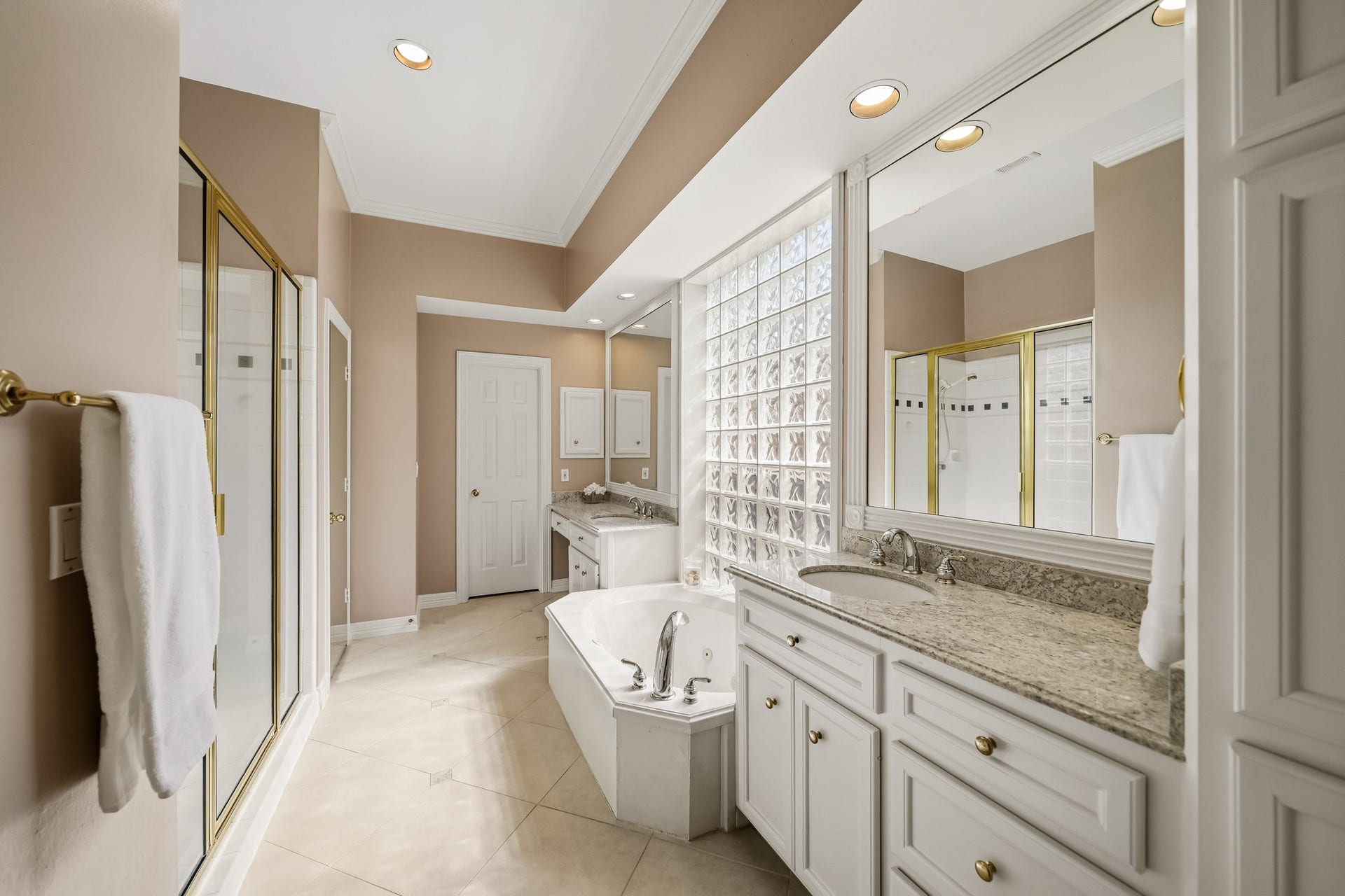 The primary bath with separate sinks, vanity, and dual closets. Updated with lovely granite countertops.  Separate tub and shower and vanity space.