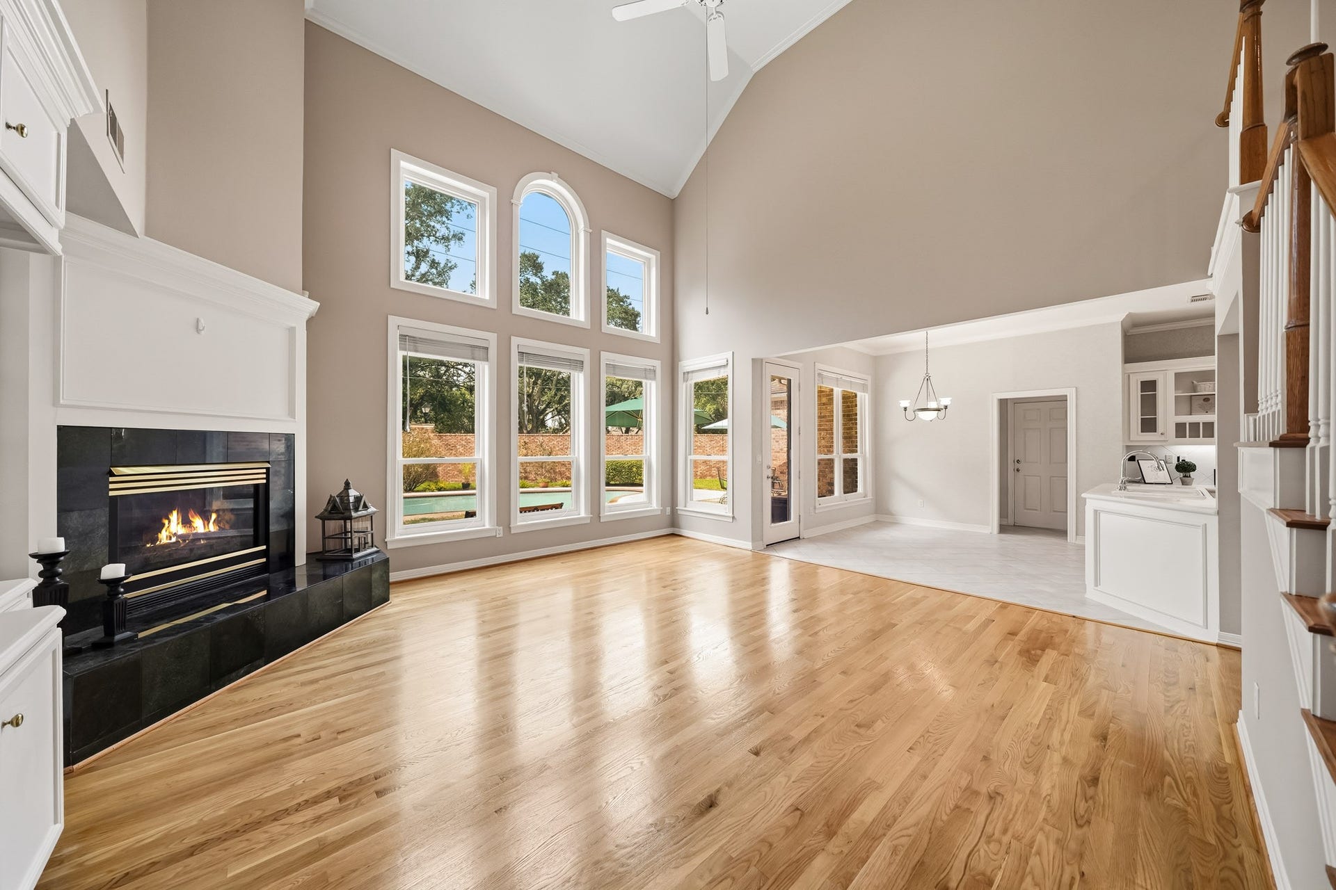 The family room with recently refinished solid hardwood flooring, neutral paint, gas log fireplace and a wall of windows with views of the pool and backyard.