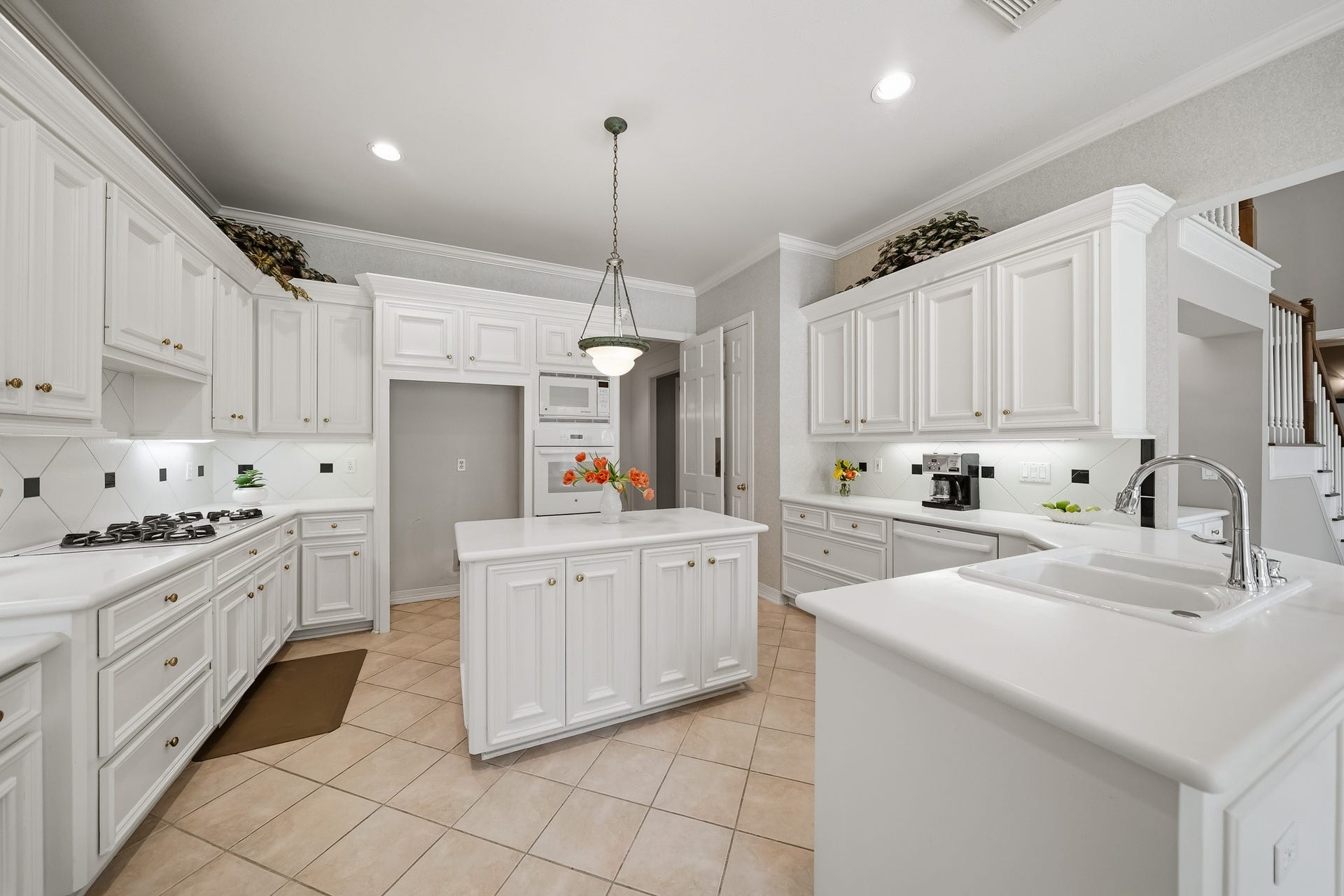 Double ovens, five burner gas stove, solid surface countertops.