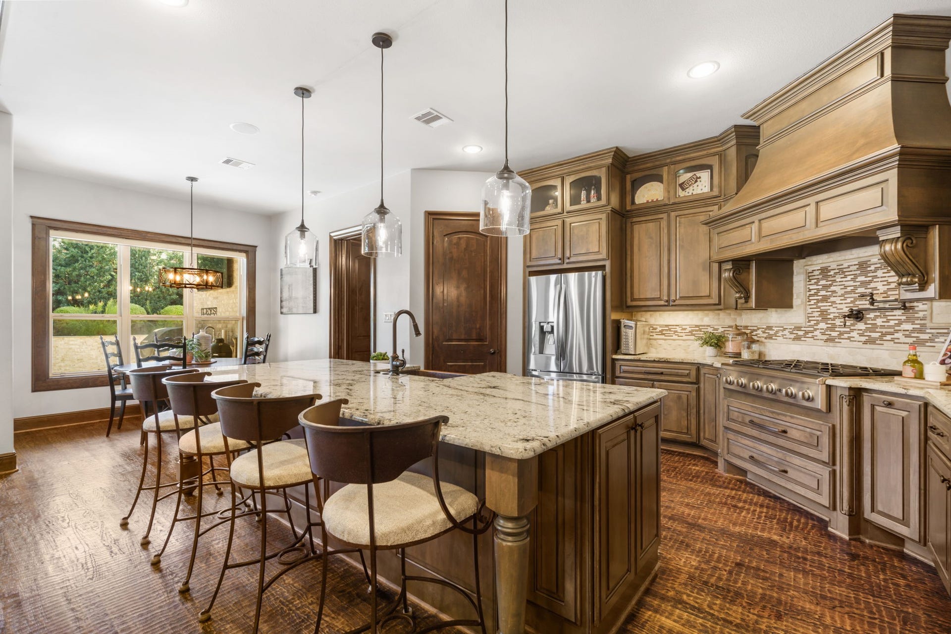 126 Summer Holly Drive, Conroe, TX 77384 Beautifully appointed kitchen featuring Benedettini custom cabinetry, granite countertops, an oversized island with breakfast bar seating, and elegant pendant lighting.
