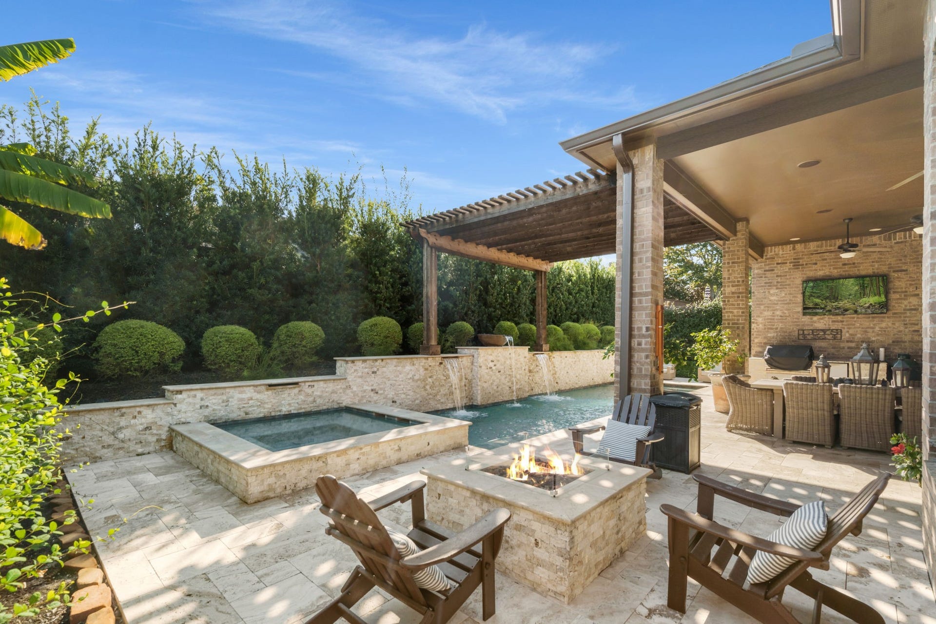 126 Summer Holly Drive, Conroe, TX 77384 Resort-style backyard featuring a sparkling pool, raised spa, inviting fire-pit, and custom water features.