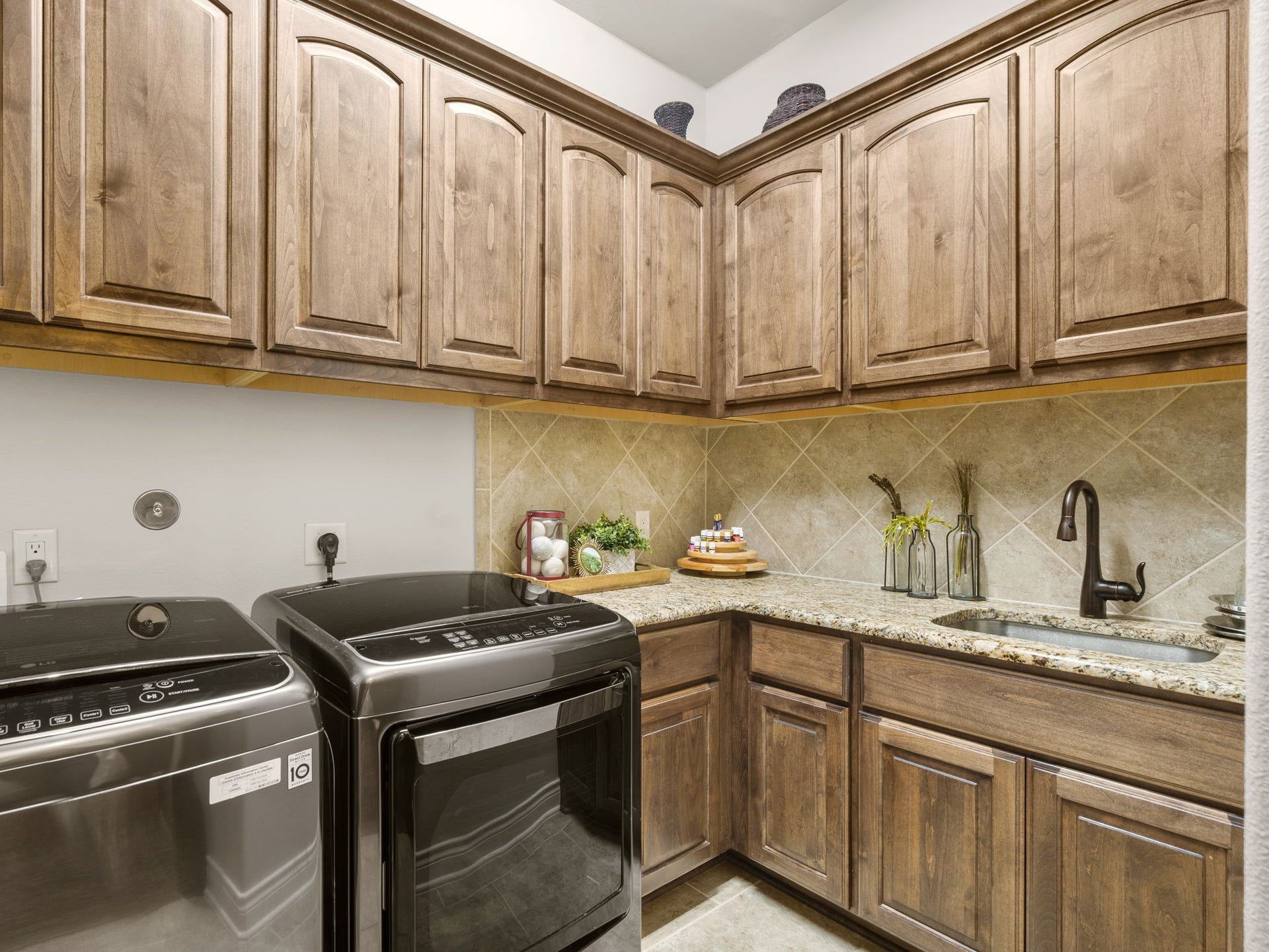 126 Summer Holly Drive, Conroe, TX 77384 Spacious utility room with abundant upper and lower cabinetry, granite countertops, utility sink, and tile flooring.