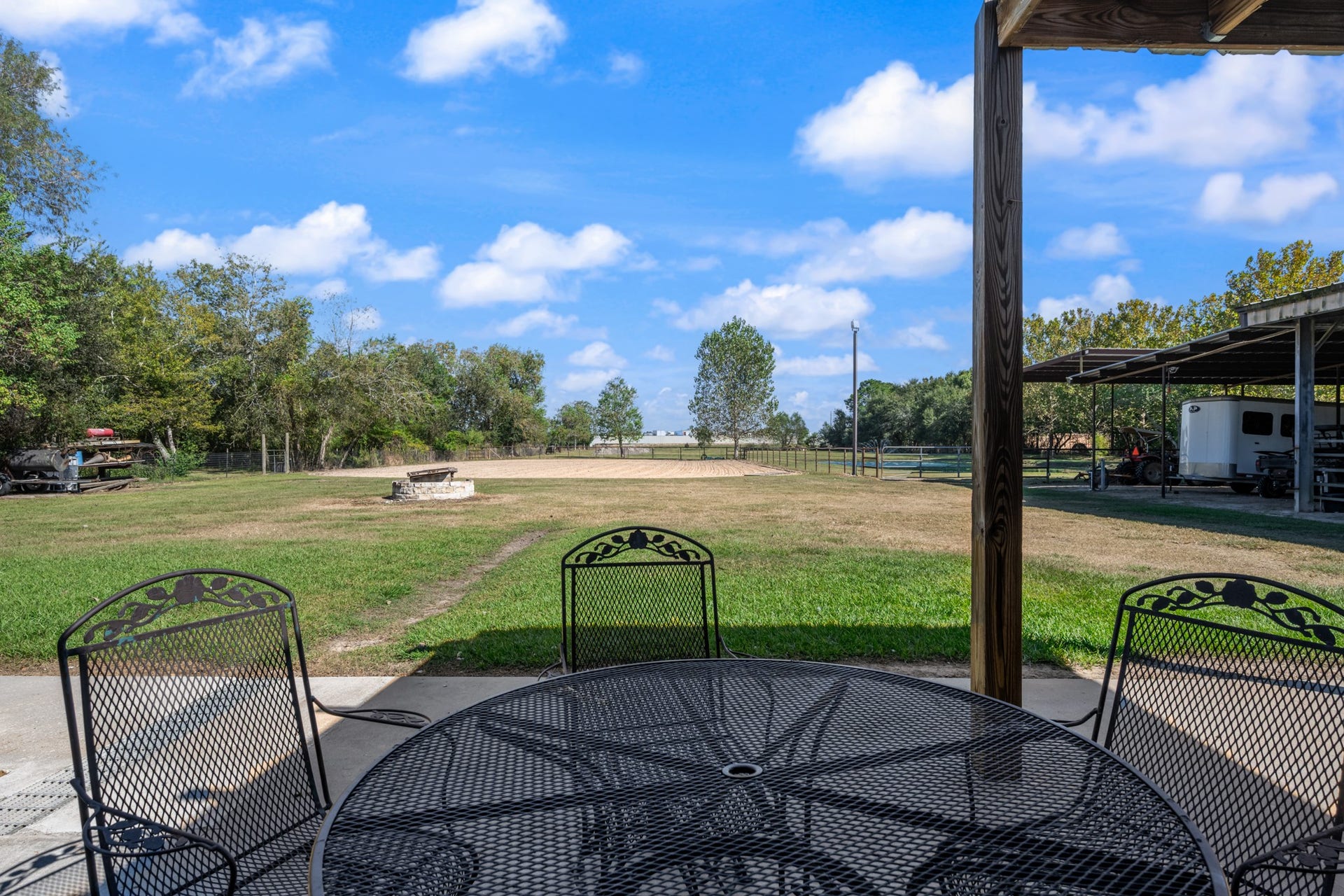 2215 Avenue Q, Santa Fe, TX 77510 Enjoy peaceful views of the property's equestrian amenities from this covered outdoor seating area. Overlooking the fenced riding arena, open green space, and covered equipment and trailer parking, this inviting spot offers the perfect place to relax while taking in the beauty of country living.