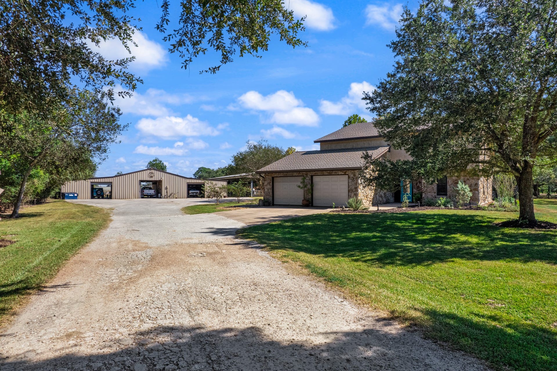 2215 Avenue Q, Santa Fe, TX 77510 A welcoming, tree-lined driveway leads to the residence and spacious outbuildings, creating a picturesque entrance to this Santa Fe horse property. Mature shade trees, expansive lawn areas, and generous parking space complement the peaceful country setting, while the large covered structures provide convenient space for vehicles, trailers, and equestrian equipment.