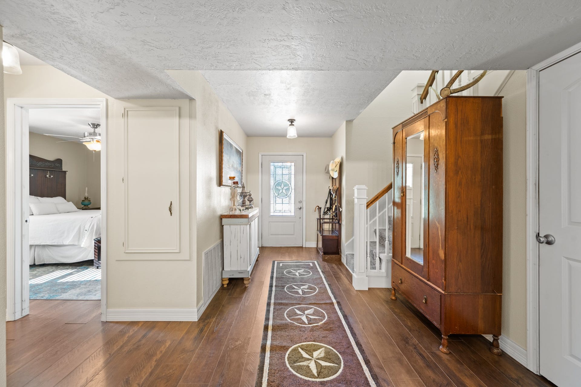 2215 Avenue Q, Santa Fe, TX 77510 Welcoming entryway showcases warm wood-look flooring, a decorative glass front door with a Texas star design, and a staircase with white balusters and wood handrail.