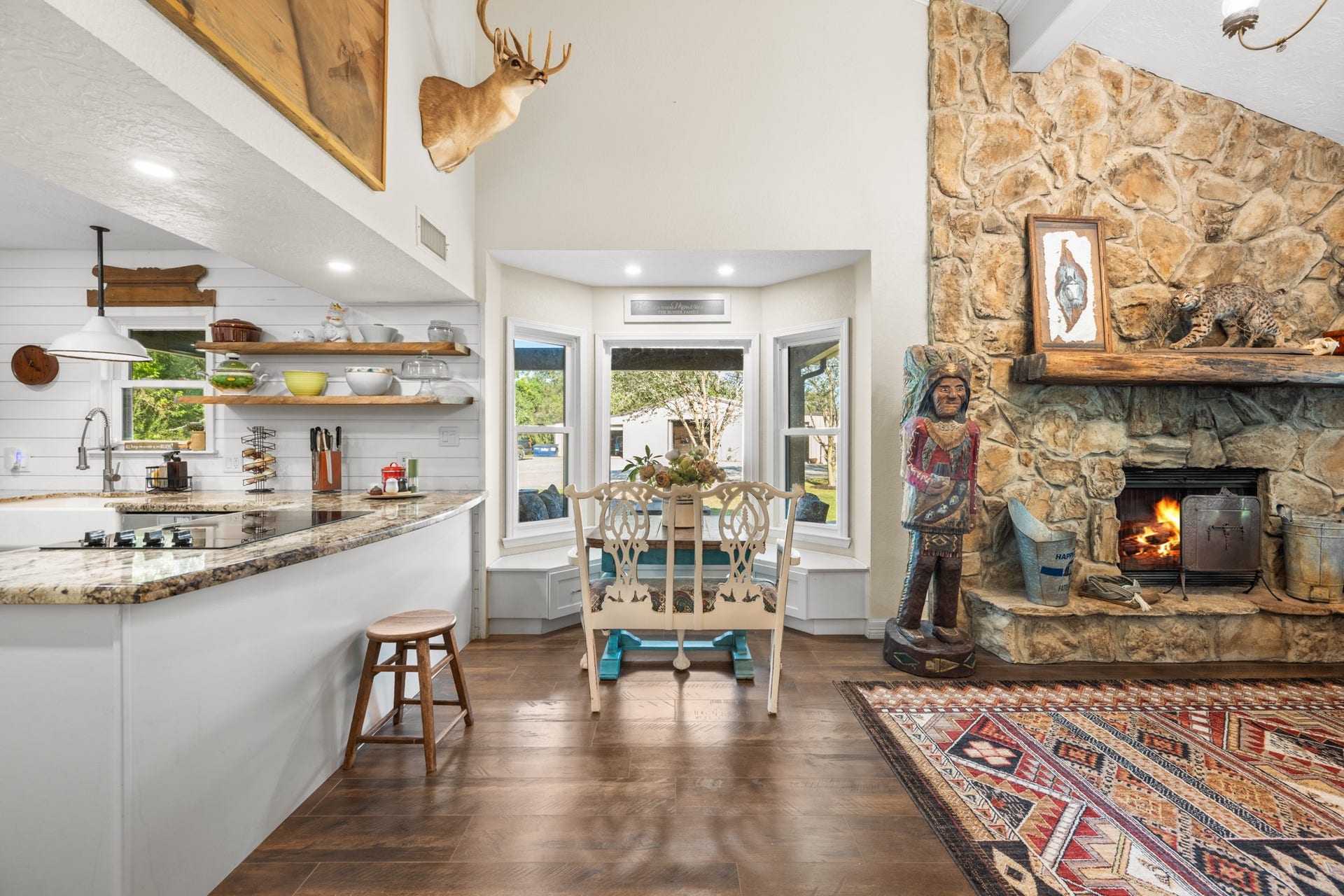 2215 Avenue Q, Santa Fe, TX 77510 A charming window-lined breakfast nook with built-in seating connects the farmhouse kitchen and living area, where soaring ceilings and a dramatic stone fireplace create an inviting atmosphere.