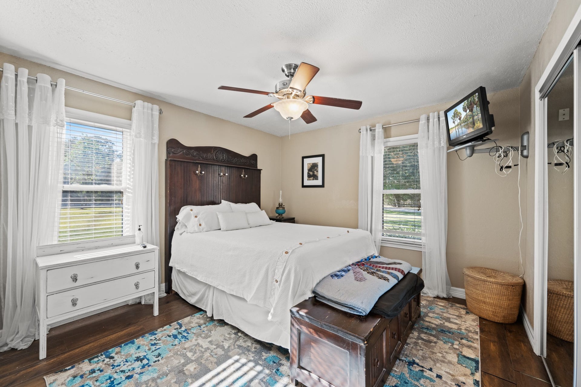 2215 Avenue Q, Santa Fe, TX 77510 Inviting downstairs guest bedroom offers two windows overlooking the property, warm wood-look flooring, a ceiling fan, and a mirrored closet.