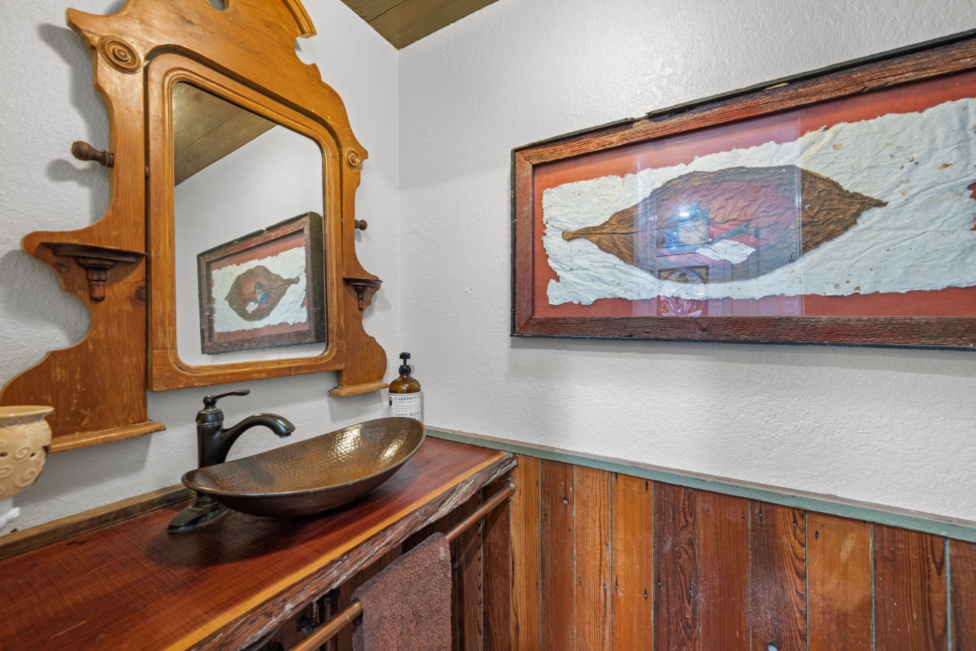 2215 Avenue Q, Santa Fe, TX 77510 Full of rustic character, this charming half bath features a distinctive hammered-metal vessel sink, rich wood countertop, vintage-style framed mirror, and warm wood wainscoting.