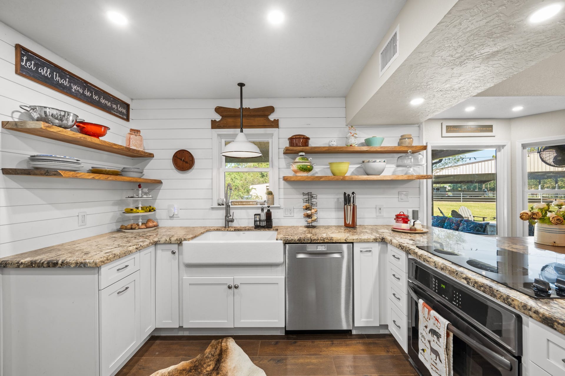 2215 Avenue Q, Santa Fe, TX 77510 A beautiful apron-front farmhouse sink, gooseneck faucet, granite countertops, and floating wood shelves combine style with everyday functionality.