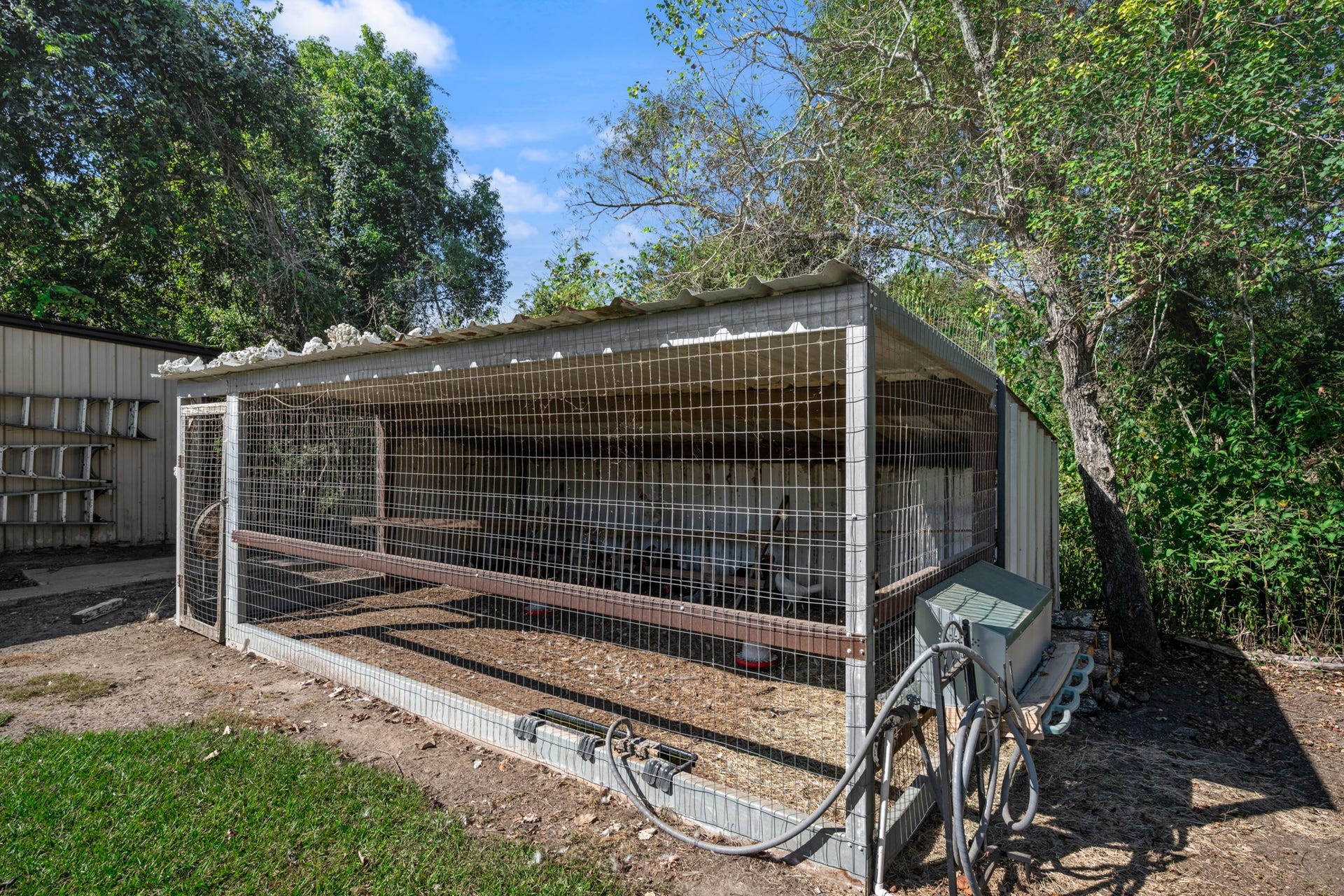 2215 Avenue Q, Santa Fe, TX 77510 Covered poultry enclosure featuring wire-mesh fencing, a metal roof, and an enclosed shelter area. The spacious setup provides a dedicated area for raising chickens or other small poultry, adding to the property's versatile country living amenities.