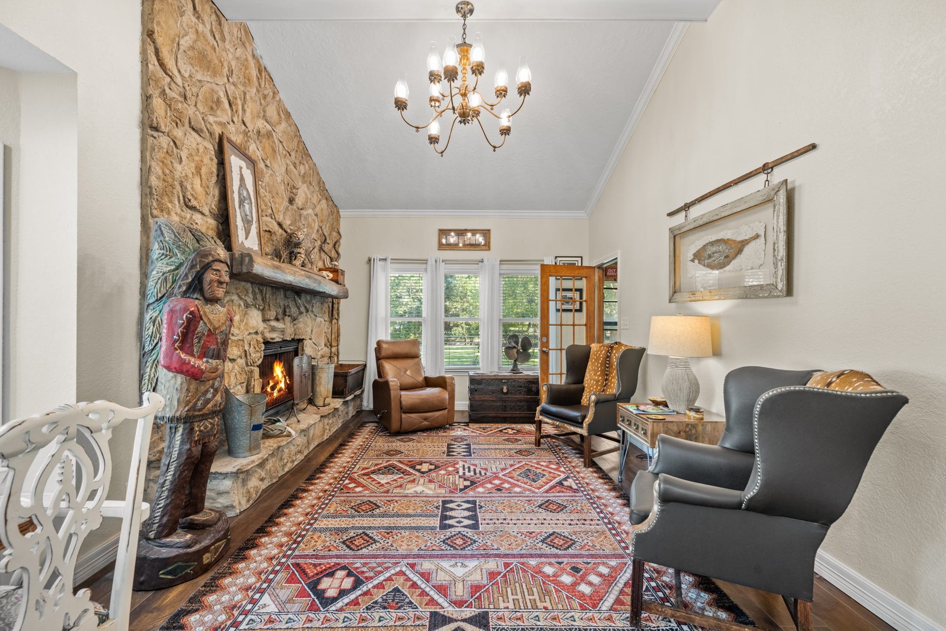 2215 Avenue Q, Santa Fe, TX 77510 A dramatic floor-to-ceiling stone fireplace anchors this inviting living room, complemented by soaring ceilings, a rustic wood mantel, and large windows overlooking the property.
