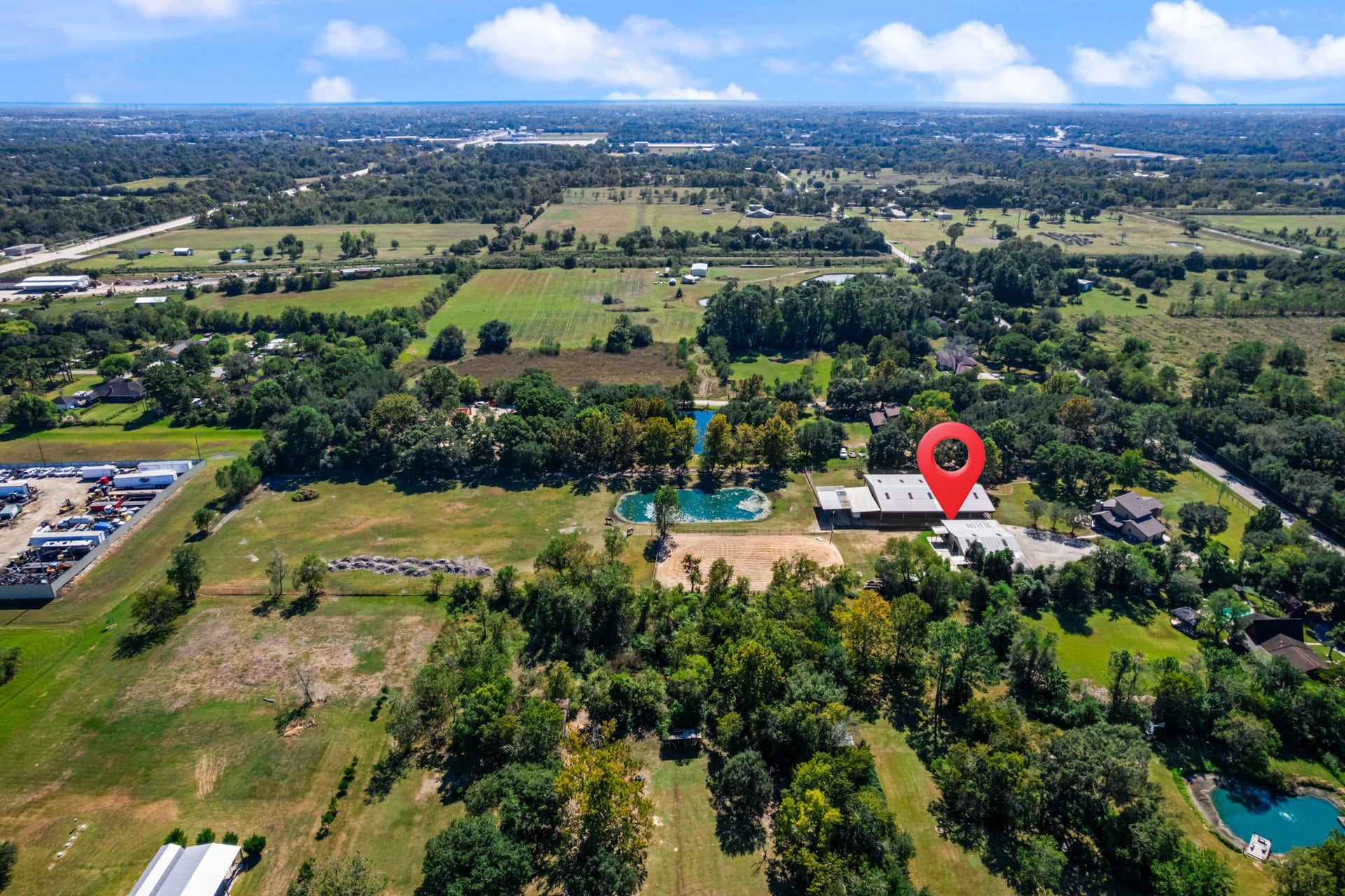 2215 Avenue Q, Santa Fe, TX 77510 A stunning aerial perspective highlights the property's spacious grounds, picturesque pond, open pasture, and equestrian facilities. Surrounded by mature trees and scenic countryside, this horse property offers a wonderful combination of rural charm, recreational opportunities, and convenient access to nearby amenities.